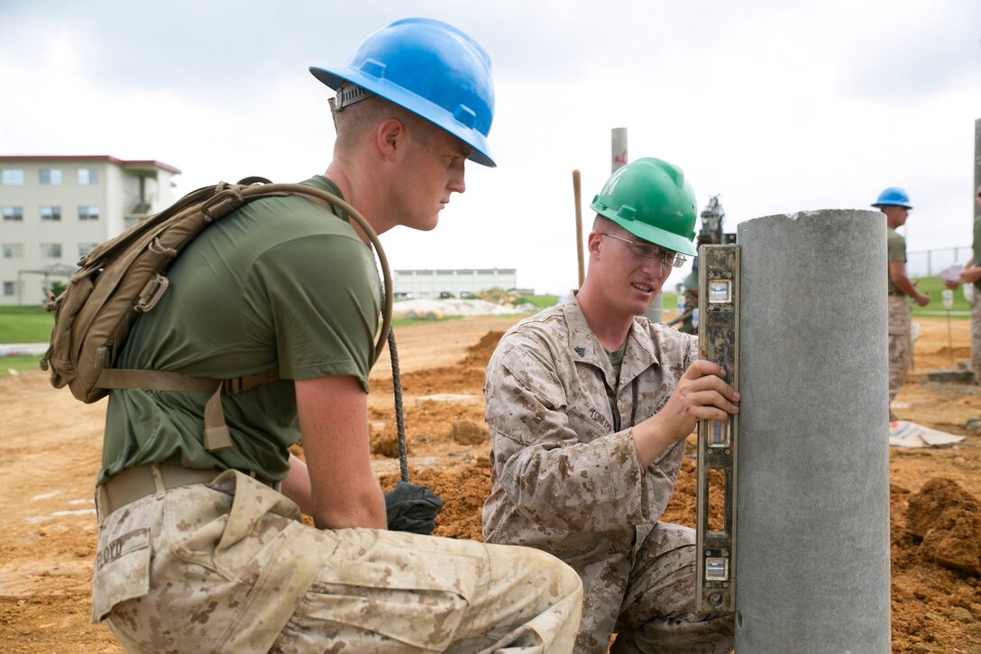 Cpl. John M. Toniolo, right, and Pfc. Wyatt M. Floyd level a concrete post during construction of an obstacle course Aug.14 on Camp Hansen. The Marines have been working on the obstacle course for over a month and are scheduled to finish by mid-September. An opening ceremony is planned for the new obstacle course’s completion. Toniolo is a Monroe, Michigan, native, and Wyatt is a Carrollton, Missouri, native. Both are combat engineers with 9th Engineer Support Battalion, 3rd Marine Logistics Group, III Marine Expeditionary Force. 