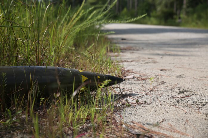 A mock artillery shell, simulating an improvised explosive device, lies on the side of a path used by Transportation Support Company, Combat Logistics Battalion 6, 2nd Marine Logistics Group during a field exercise aboard Marine Corps Base Camp Lejeune, N.C., Aug. 20, 2014. Marines, playing the role of enemy combatants, set up simulated IEDs and ambushes to aid in the realism of the training.