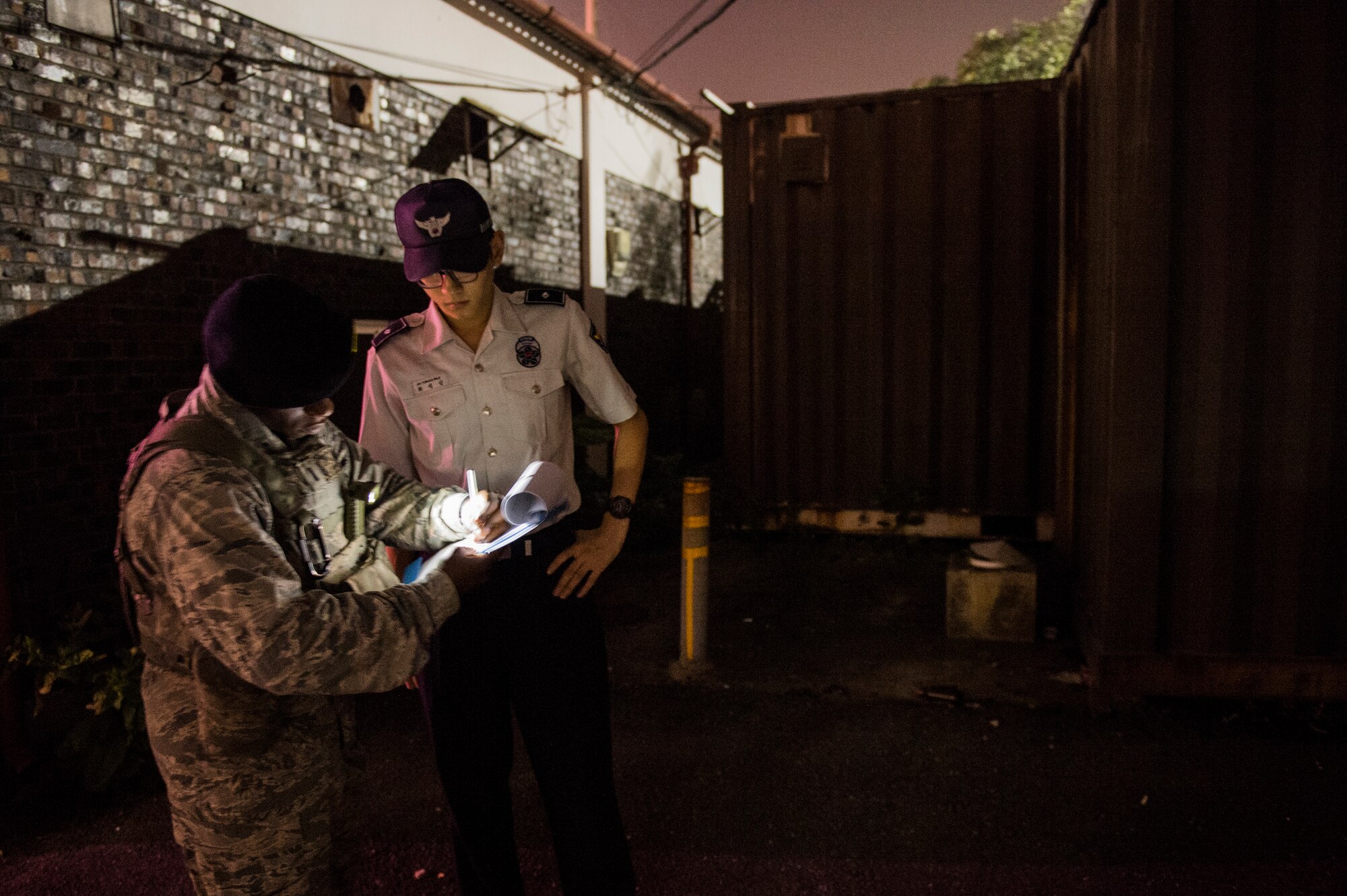 U.S. Air Force and Republic of Korea Air Force members with the 8th Security Forces Squadron check paperwork before starting their patrols in American Town outside of Kunsan Air Base, Republic of Korea, Aug. 22, 2014. The 8th SFS works with ROKAF to conduct town patrols on the weekends to remind Airmen to be safe and make smart choices. (U.S. Air Force photo by Staff Sgt. Stephany Richards/ Released)