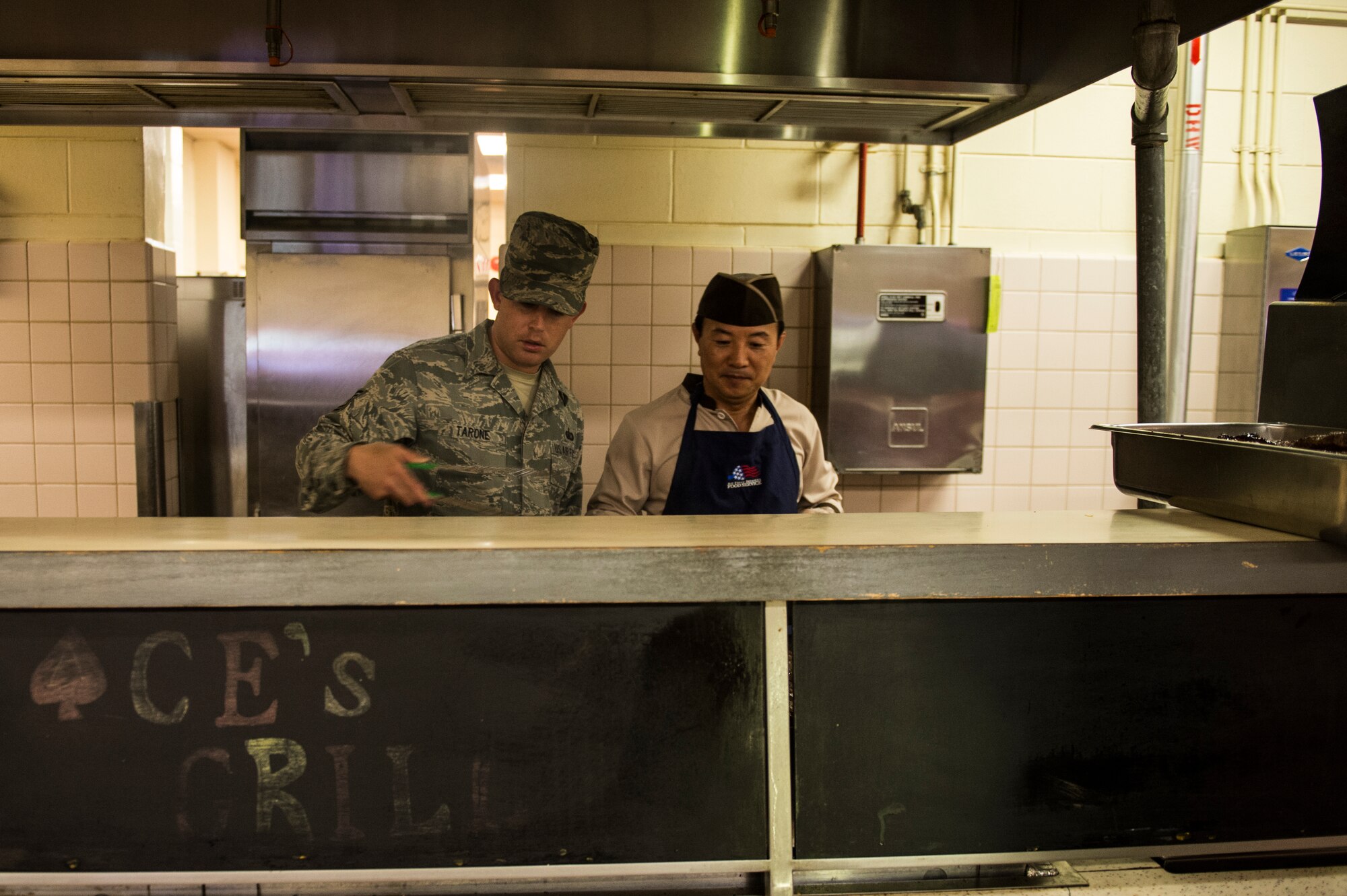 U.S. Air Force Tech. Sgt. James Tarone, 8th Force Support Squadron dining facility manager, prepares steaks with Republic of Korea Air Force Mr. Myong Pae Kim at Kunsan Air Base, Republic of Korea, Aug. 21, 2014. The 8th Mission Support Group works closely with ROKAF counterparts to support base needs. (U.S. Air Force photo by Staff Sgt. Stephany Richards/ Released)