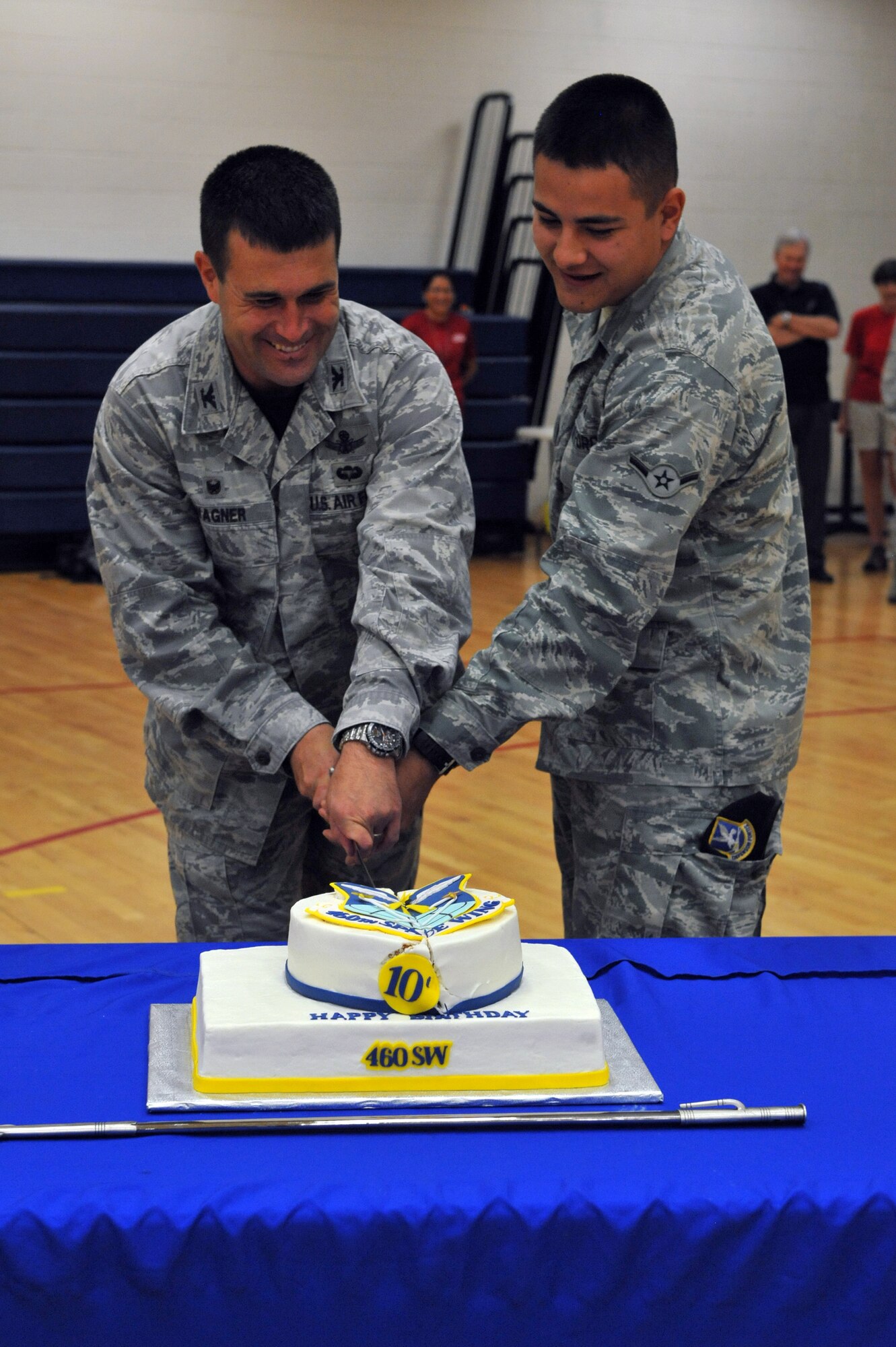 Col. John Wagner, 460th Space Wing commander, cuts the cake with Airman Emilio Munoz-Shade, 460th Security Forces Squadron apprentice, during FunFest Aug. 22, 2014 on Buckley Air Force Base, Colo. The 460th Space Wing celebrated its 10th birthday with FunFest, a day filled with sport competitions and a community fair. (U.S. Air Force photo by Airman Emily E. Amyotte/Released)