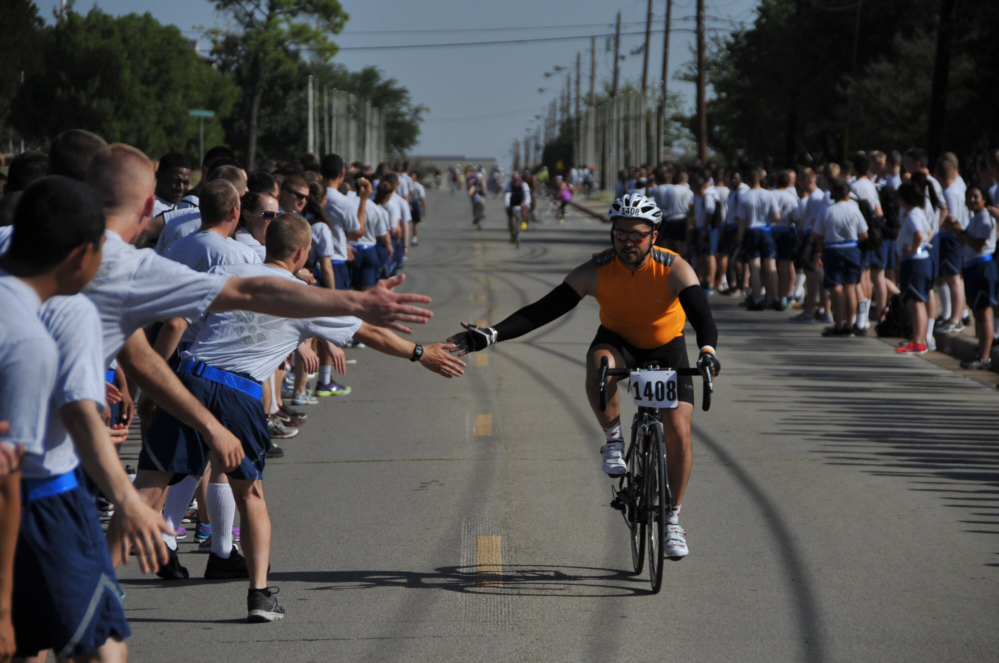 A Hotter’N Hell participant exchanges high-fives with Airmen-in-Training as he passes through Airmen’s Alley during the Hotter’N Hell bike race Aug. 23, 2014. Airmen’s Alley was filled with hundreds of AiT’s from different training Squadrons who cheered on the thousands of cyclists riding through Sheppard Air Force Base, Texas. (U.S. Air Force photo/Airman 1st Class Robert L. McIlrath)