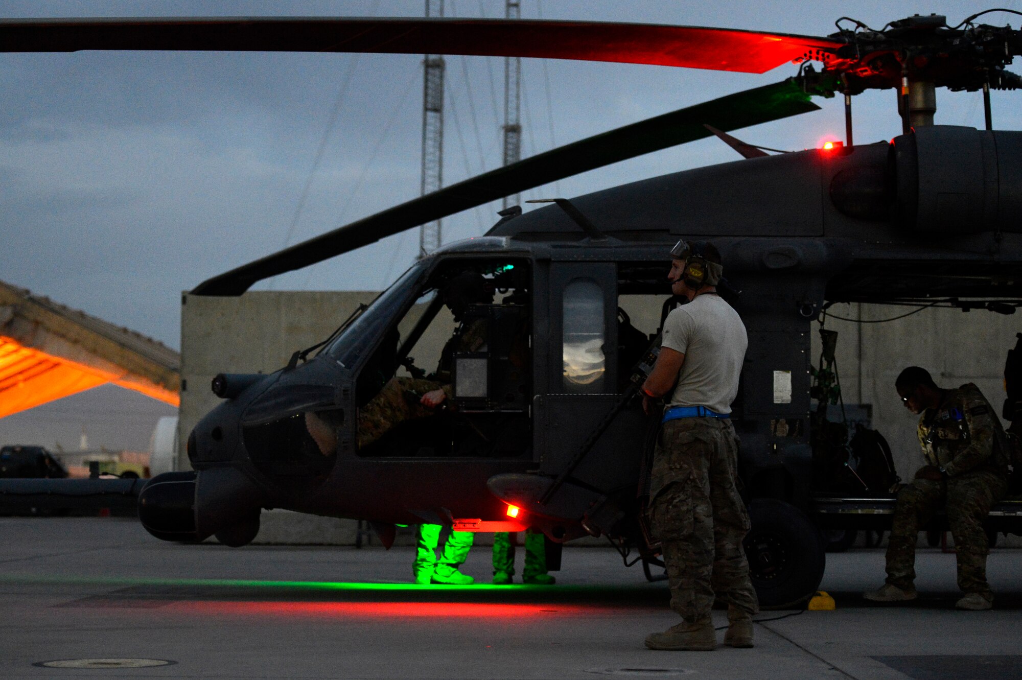 Senior Airman Matthew Des Jardins, 455th Expeditionary Aircraft Maintenance Squadron crew chief, waits as the assigned Pararescue team performs communication checks with the HH-60G Pave Hawk helicopter before taking off from Bagram Air Field, Afghanistan, July 9, 2014. Des Jardins, a Peoria, Illinois native, is deployed from the 923rd Aircraft Maintenance Squadron, Davis-Monthan Air Force Base, Arizona. (U.S. Air Force photo by Senior Airman Sandra Welch/Released)
