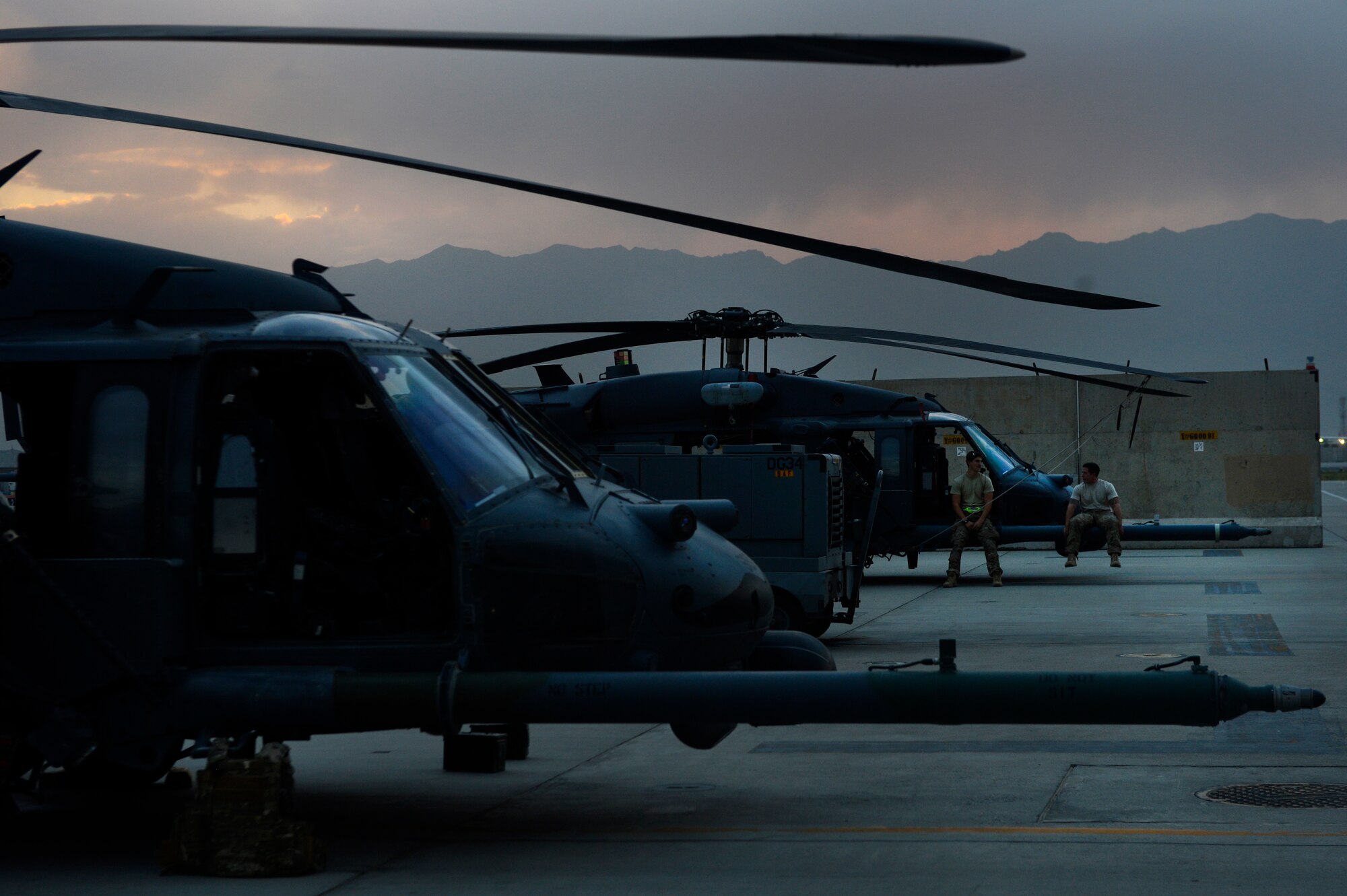 Senior Airman Lucas Brogdon, 455th Expeditionary Aircraft Maintenance Squadron crew chief, and Senior Airman Cody Ficsher, 455th EAMXS communication and navigation specialist, wait for an HH-60G Pave Hawk helicopter to take-off from Bagram Air Field, Afghanistan, July 9, 2014. Brogdon, a Lexington, North Carolina native, and Ficsher, a Visalia, California native, are deployed from the 923rd Aircraft Maintenance Squadron, Davis-Monthan Air Force Base, Arizona. (U.S. Air Force photo by Senior Airman Sandra Welch/Released)