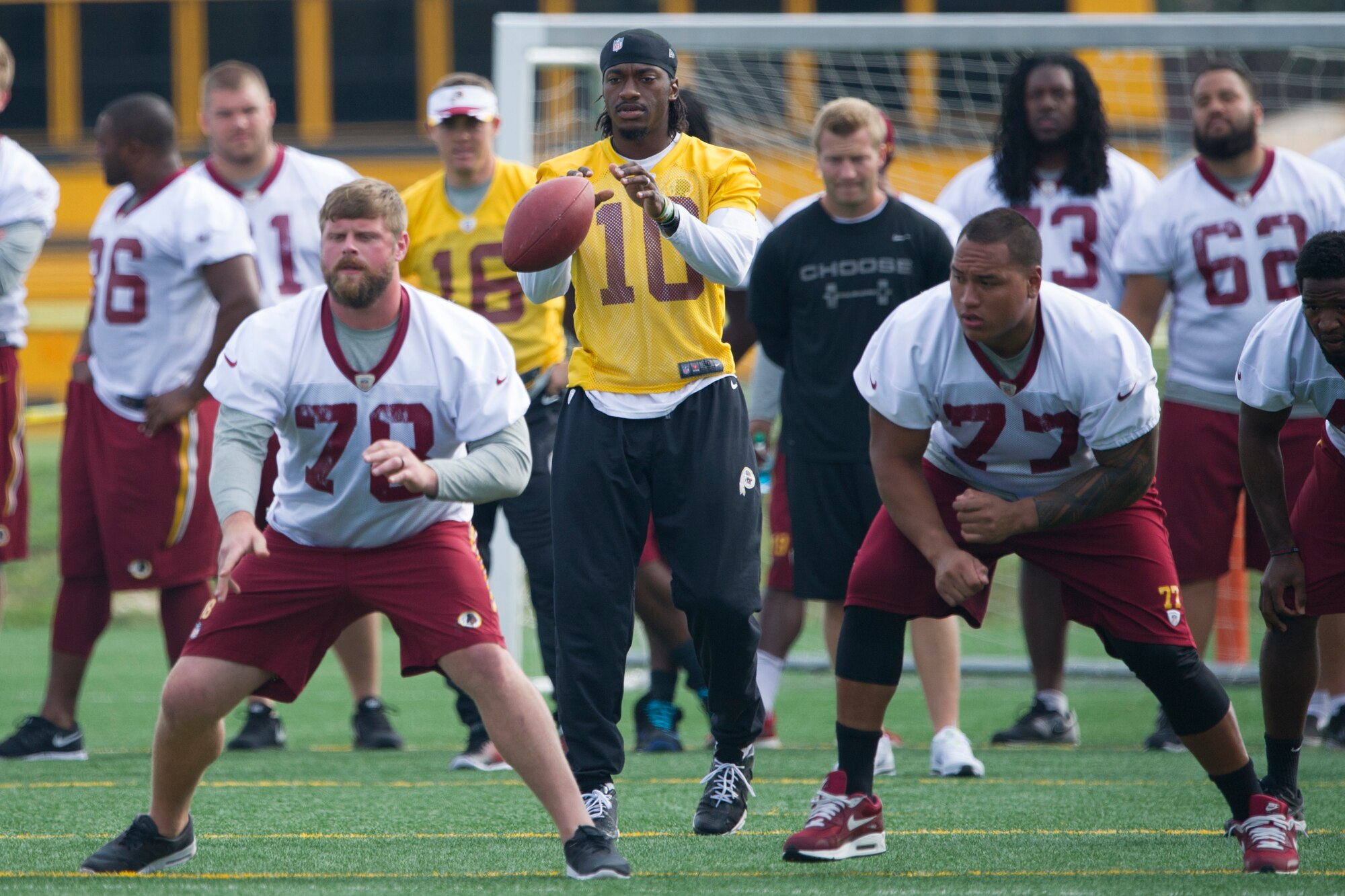 Washington Redskins quarterback Robert Griffin III, takes a snap from Kory Lichtensteiger, a Redskins center, at Joint Base Andrews August 22,2014. The team performed a walk-through practice and signed autographs for military members and their families as part of their Redskins Salute effort. (U.S. Air Force photo/Staff Sgt. Robert Cloys)