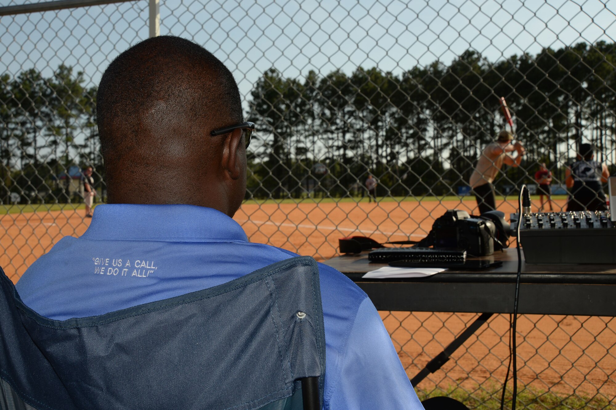 Derrick Rhems, 20th Force Support Squadron marketing and promotions director, sits inside the announcer tent during Shaw’s family fun night at Shaw Air Force Base, S.C., Aug. 21, 2014. Rhems provided play-by-play broadcasting during the family fun night softball games.  (U.S. Air Force photo by Airman 1st Class Michael Cossaboom/Released)