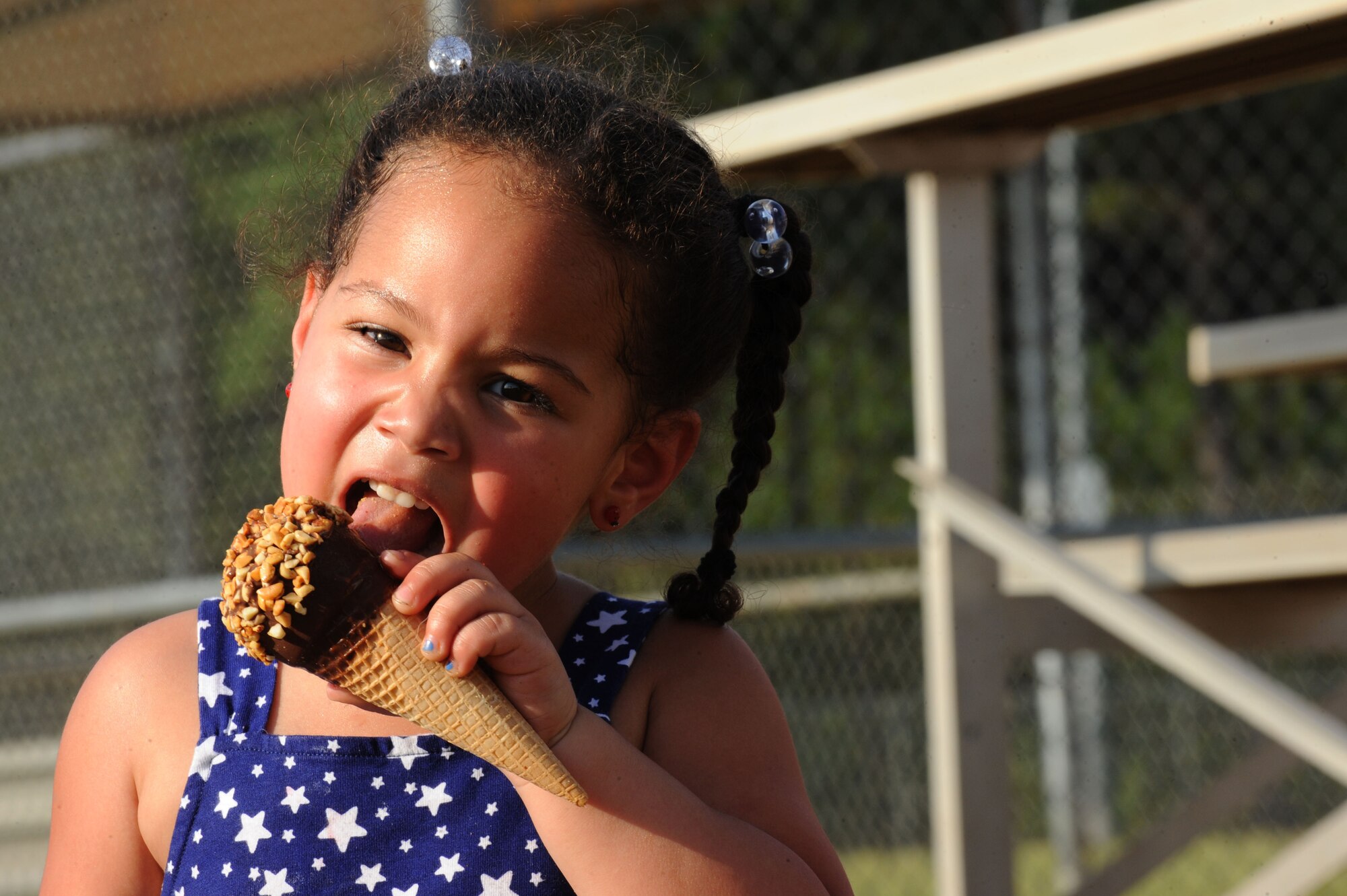 Mya, daughter of Tech. Sgt. Steven Dagnan, 337th Recruiting Squadron recruiter, eats an ice cream cone during Shaw’s family fun night at Shaw Air Force Base, S.C., Aug. 21, 2014. During the event, members from the 20th Operational Support Squadron, First Sergeant Council, and 337th RCS sold snacks, drinks, and t-shirts. (U.S. Air Force photo by Airman 1st Class Michael Cossaboom/Released)
