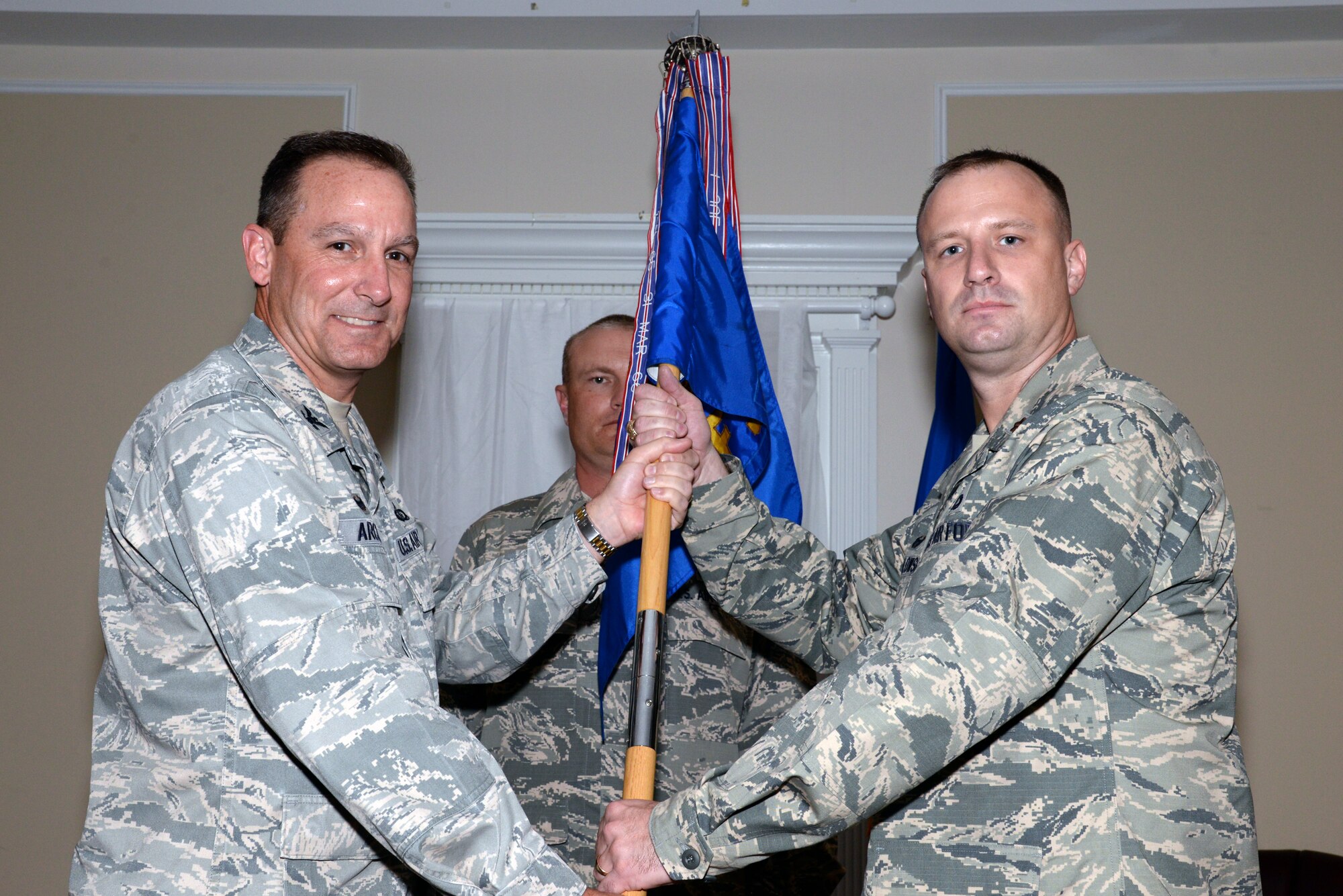 U.S. Air Force Maj. S. Nathan Puwalowski, 20th Security Forces Squadron commander (right), receives the 20th SFS guidon from Col. Scott Arcuri, 20th Mission Support Group commander, during a change of command ceremony at Shaw Air Force Base, S.C., Aug. 21, 2014. The tradition of passing the guidon goes back to 18th century Prussia; during this time, organizational flags were developed with color arrangements and symbols unique to the particular military unit. (U.S. Air Force photo by Airman 1st Class Jonathan Bass/Released)