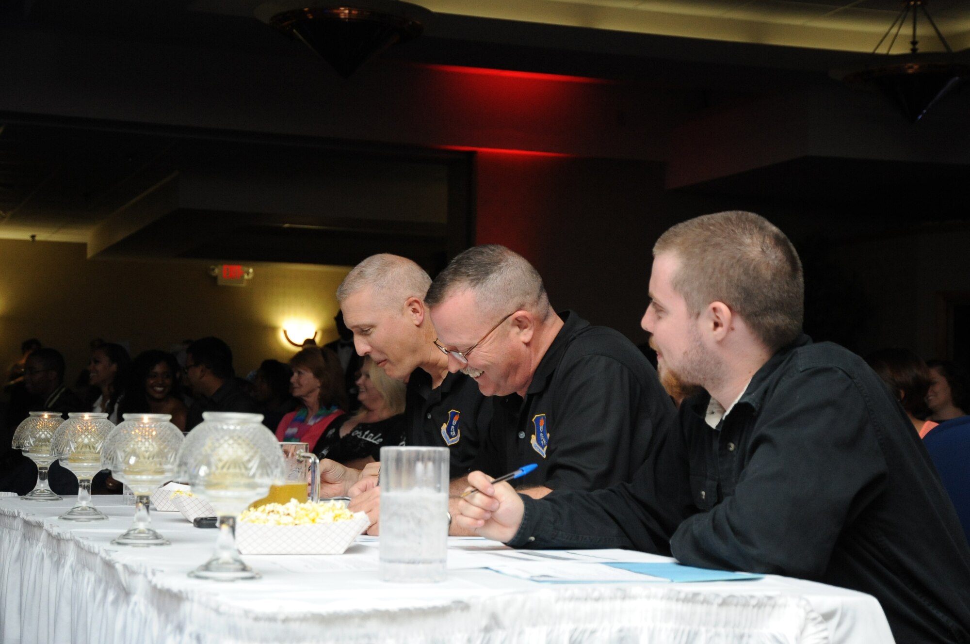 (From left) Col. Paul Bauman, 319th Air Base Wing commander, 319th ABW Command Chief Master Sgt. David Duncan and Lance Duncan fill out judges ballots during the AMC Icon singing competition at the Northern Lights Club on Grand Forks Air Force Base, Aug. 22, 2014. Fifteen contestants competed for the opportunity to represent the base at the main AMC Icon event at Scott AFB, Ill., and a possible spot in the Air Force entertainment troupe Tops in Blue. (U.S. Air Force photo/Staff Sgt. David Dobrydney)