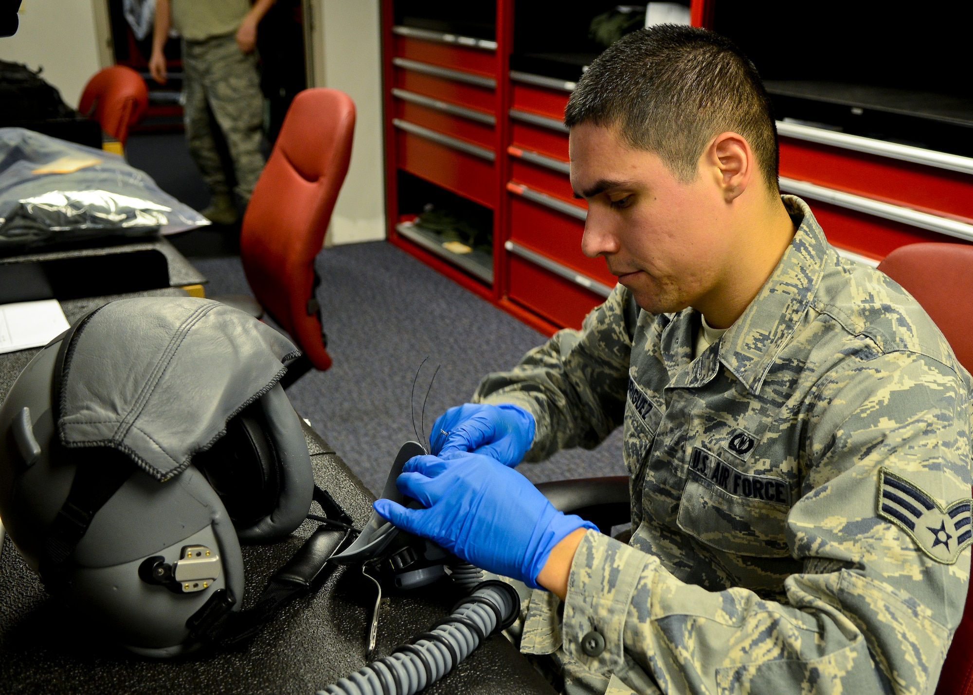 U.S. Air Force Senior Airman Robert Rodriguez, 1st Operations Support Squadron Aircrew Flight Equipment journeyman, sews a buckle onto a helmet at Langley Air Force Base, Va., Dec. 20, 2013.  AFE Airmen perform operator maintenance and service inspections on various pieces of equipment including helmets, survival kits, night vision goggles and other types of AFE equipment. Rodriguez Santa Maria, California, (U.S. Air Force photo by Airman 1st Class Victoria H. Taylor/ Released)