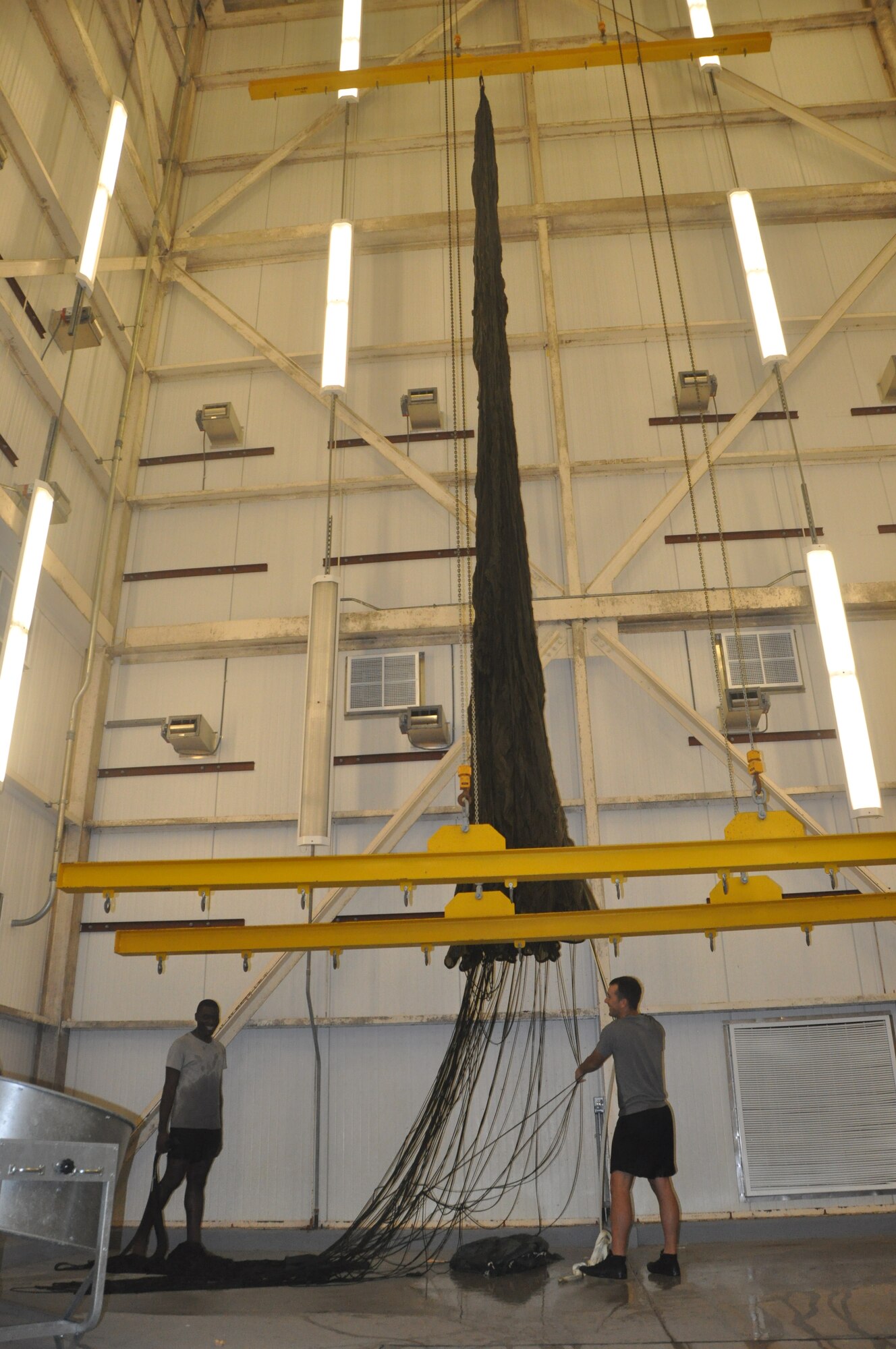 Reserve Aircrew Flight Equipment specialists from the 308th Rescue Squadron raise a parachute to be dried after a salt-water pararescue mission, August 19, 2014.  Patrick Air Force Base, Fla. Their primary responsibility is to pack, maintain and inspect parachutes and package cargo to be dropped from aircraft. (U.S. Air Force photo/ Tech. Sgt. Katie Spencer)