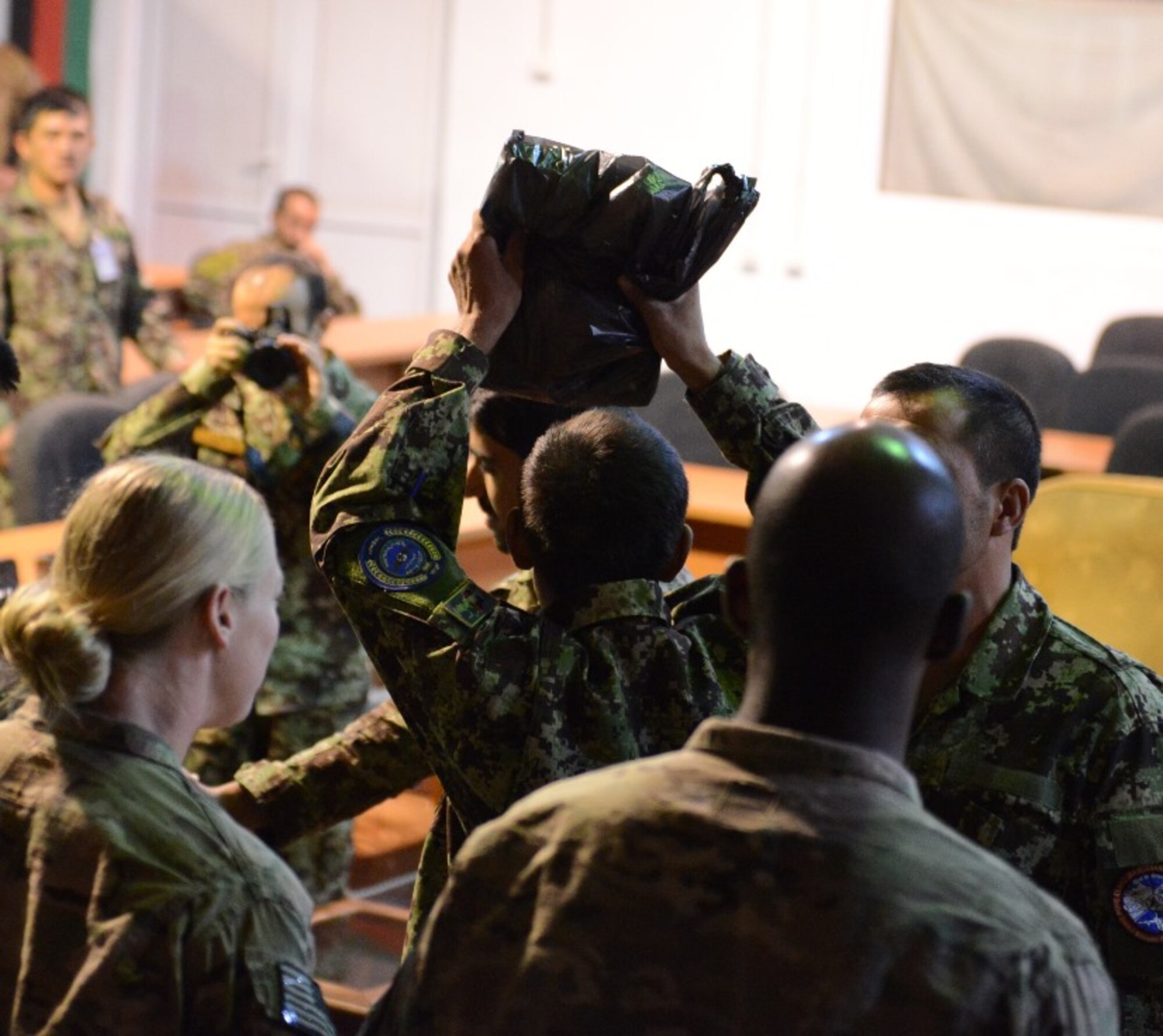 An enlisted member of the Afghan armed forces proudly raises his bag of school supplies over his head after receiving the gift from U.S. Air Force air advisors at the Afghan Air Force's Kabul Air Wing on Kabul International Airport, Afghanistan, Aug. 25, 2014. With the help of first sergeants around the Air Force, more than 3,700 items of school supplies were donated -- allowing 126 Afghan servicemembers to bring home a bag to their families. (U.S. Air Force photo/Senior Master Sgt. Mike Hammond)