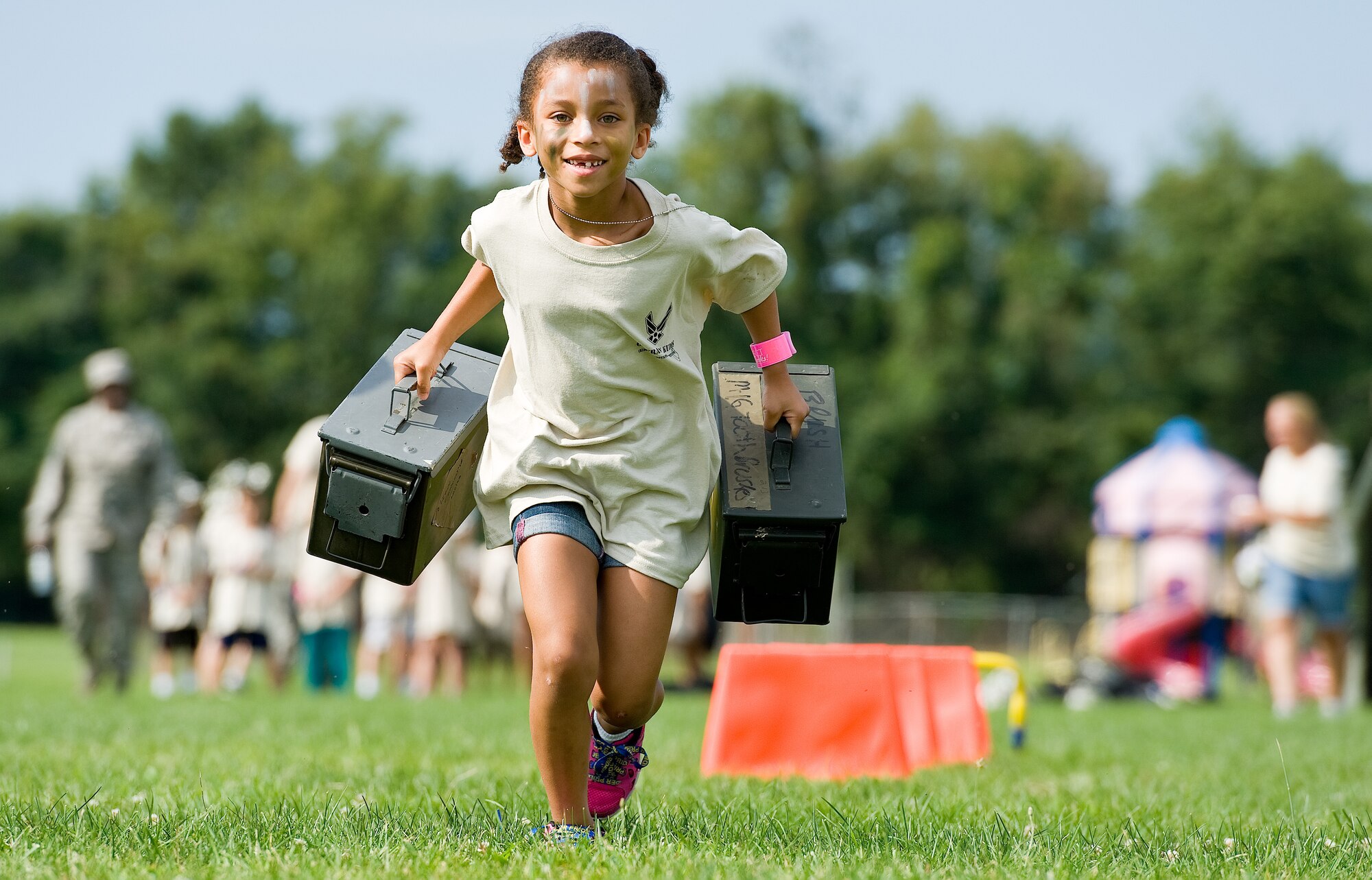 Azaniah Jones, daughter of Tech. Sgt. Alisha Navarro, 436th Security Forces Squadron, runs with two empty ammunition containers Aug. 20, 2014, at the Youth Center on Dover Air Force Base, Del. Jones and 160 other children went through a simulated deployment processing line and numerous obstacle courses during Operation KUDOS, Kids Understanding Deployment Ops that informed them on deployment preparation and procedures. (U.S. Air Force photo/Roland Balik)