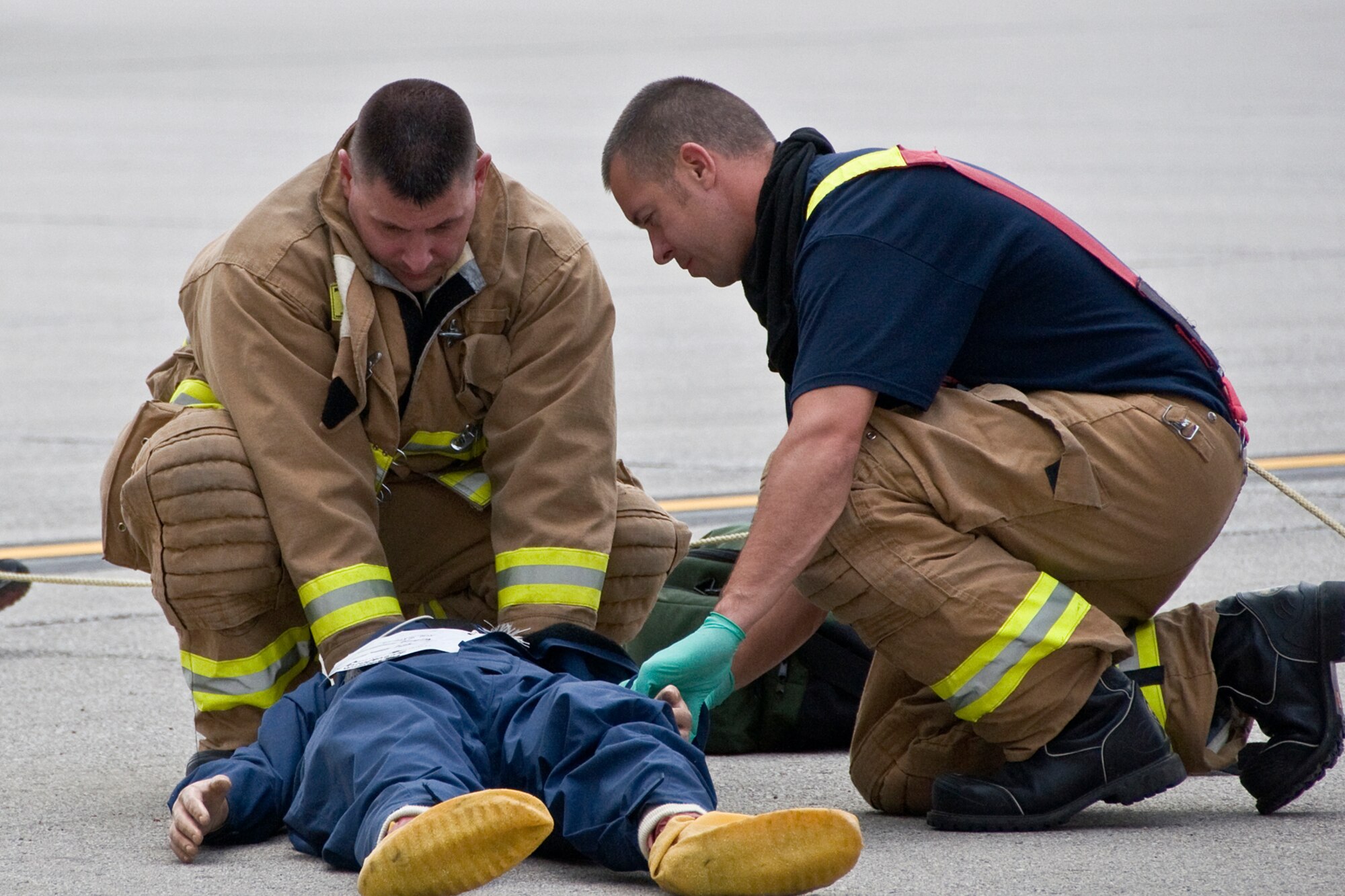 Grissom Fire Department firefighters Adam Ventsias, left, and Jay Salmons, right, provide patient care to a simulated patient during a fuel-cell extraction exercise at Grissom Air Reserve Base, Ind., Aug. 10, 2014. The annual exercise calls for maintenance and first responders to coordinate efforts in an attempt to rescue a simulated victim from a narrow inner opening to a fuel cell. (U.S. Air Force photo/Staff Sgt. Ben Mota)