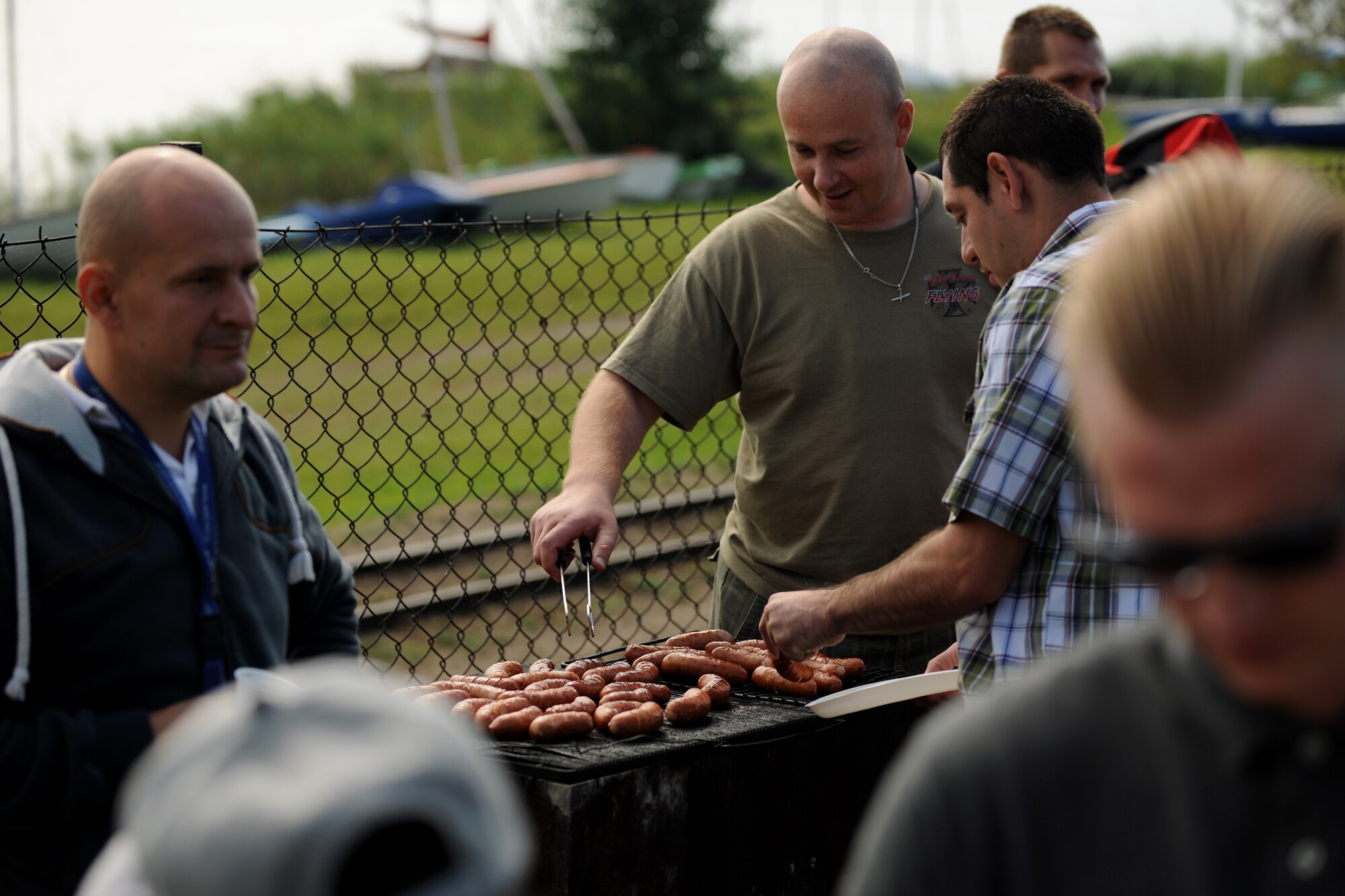 Polish Army 1st Lt. Waldemar Jarowicz, 33rd Air Transport Base C-130E copilot, center, monitors the grill during a barbecue between U.S. and Polish Service members at Powidz Lake, Poland, Aug. 22, 2014. The event brought the services together in the spirit of cultural sharing and unity. (U.S. Air Force photo by Staff Sgt. Jarad A. Denton/Released)
