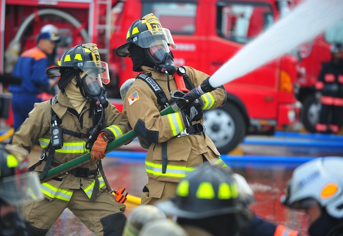 Shota Sotokawa and U.S. Air Force Airman 1st Class Erasmo Boggs, 35th Civil Engineer Squadron firefighters, direct water onto a simulated burning building during a Major Accident Response Exercise at Rokkasho Village, Japan, Aug. 19, 2014. Firefighters from the 35 CES fire department were evaluated on timeliness and effectiveness of their response capabilities. (U.S. Air Force photo by Senior Airman Jose L. Hernandez-Domitilo/Released)
