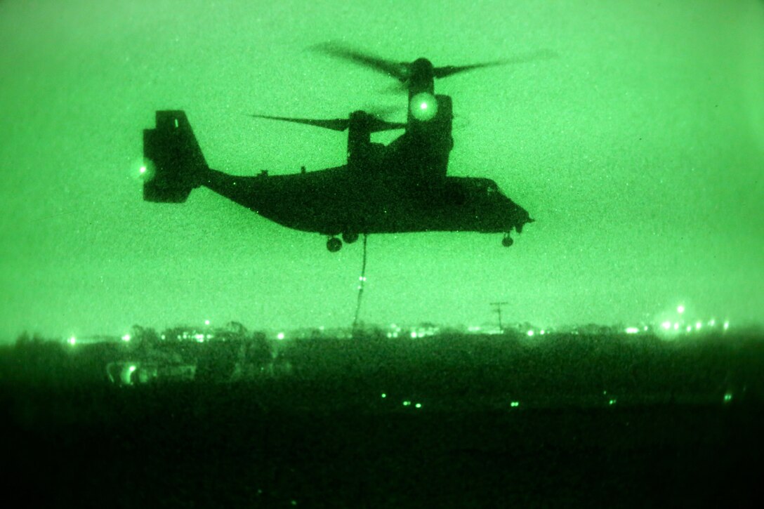 As seen through a night-vision device, a U.S. MV-22 Osprey aircraft supports Marine Helicopter Support Team during slingload operations on Marine Corps Air Station Miramar, Calif., Aug. 18, 2014. The aircraft crew is assigned to Landing Support Company, Headquarters Regiment, 1st Marine Logistics Group. Helicopter support teams consist of up to eight Landing Support Marines who are trained to hook up external loads to military helicopters providing efficient transportation of gear and supplies.