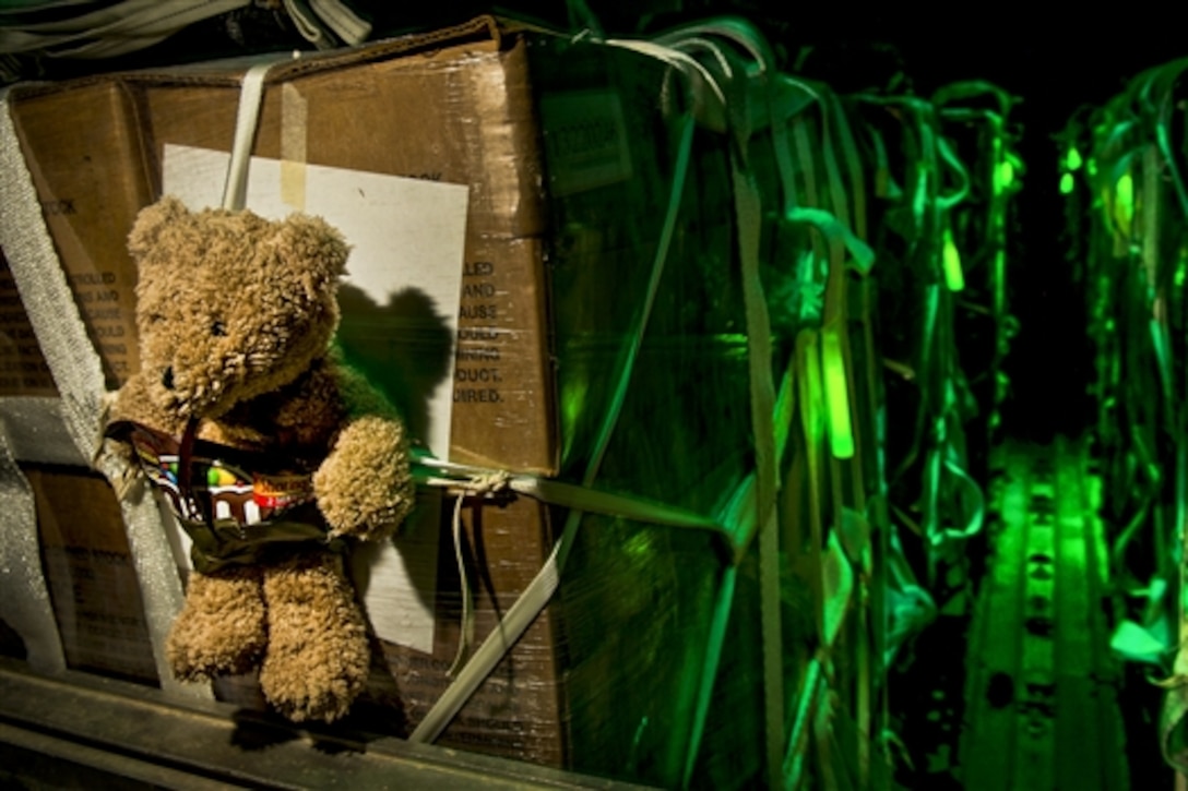 A teddy bear accompanies a halal meal in a C-130 Hercules before a humanitarian airdrop over Iraq, Aug. 14, 2014. An American child donated the teddy bear to offer support for children trapped in the Iraq conflict. U.S. airmen assisted with the airdrop, which included bottled water and food for displaced citizens of Sinjar, Iraq. Brawley is a loadmaster assigned to the 746th Expeditionary Airlift Squadron.