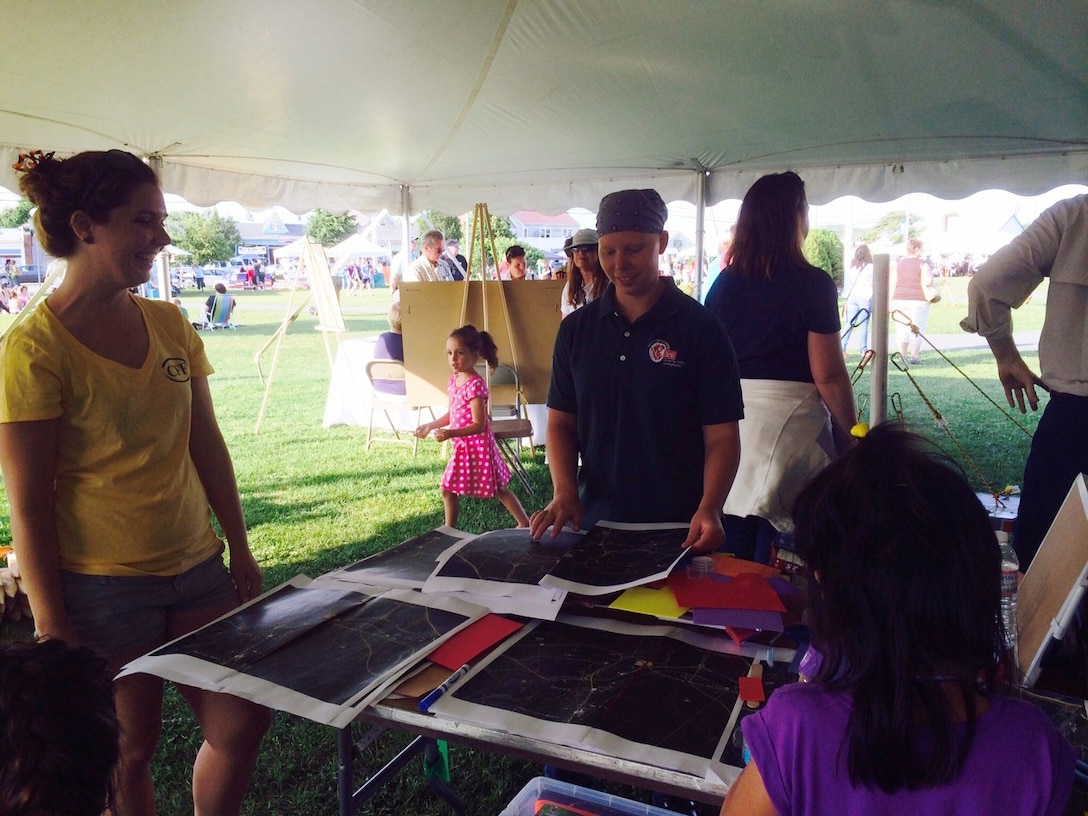 Kristen Paul (right) works with children on the Cape Cod Canal City Urban Planning activity under the Boston Society of Civil Engineers Section engineering tent. The STEM event took place during the Cape Cod Canal's 100th anniversary celebration, July 29, 2014.