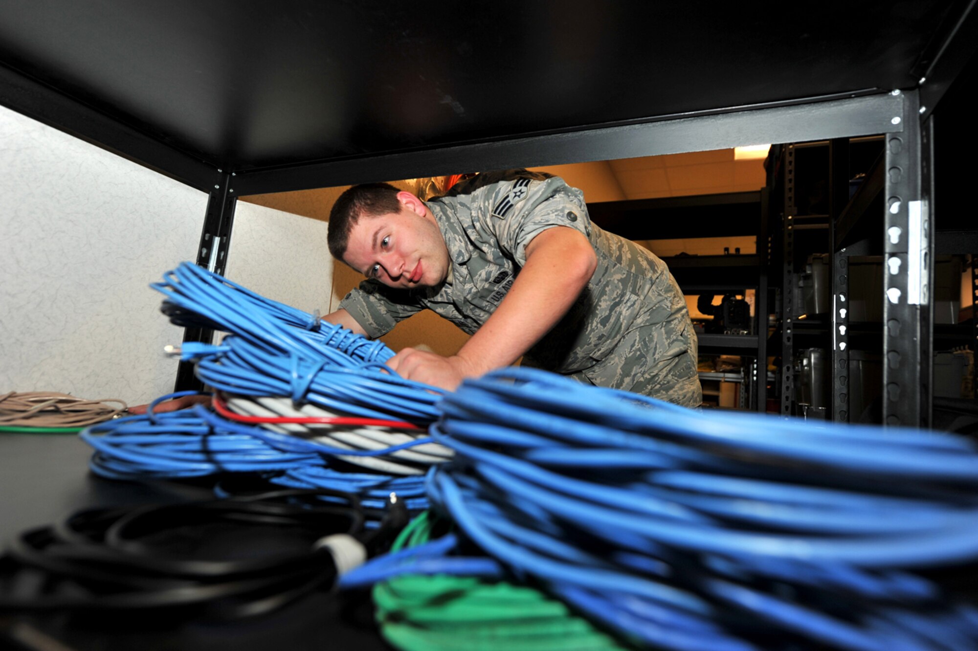 Senior Airman Lee Owens, former 42nd Air Base Wing broadcast engineer, secures local area network cables on a storage shelf, July 24, 2014. Owens was one of more than 3,500 Airmen selected for separation after being identified by the Air Force's first Quality Force Review Board. After five years in uniform Owens faces rejoining the civilian sector with a smile and an appreciation for the military. (U.S. Air Force photo by Master Sgt. Michael Voss)  