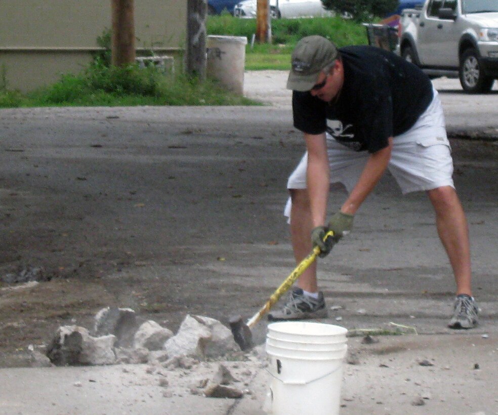 Tom O’Hara, III, Omaha District Executive Officer, breaks down the old cement porch step into smaller pieces with the force of a sledgehammer.