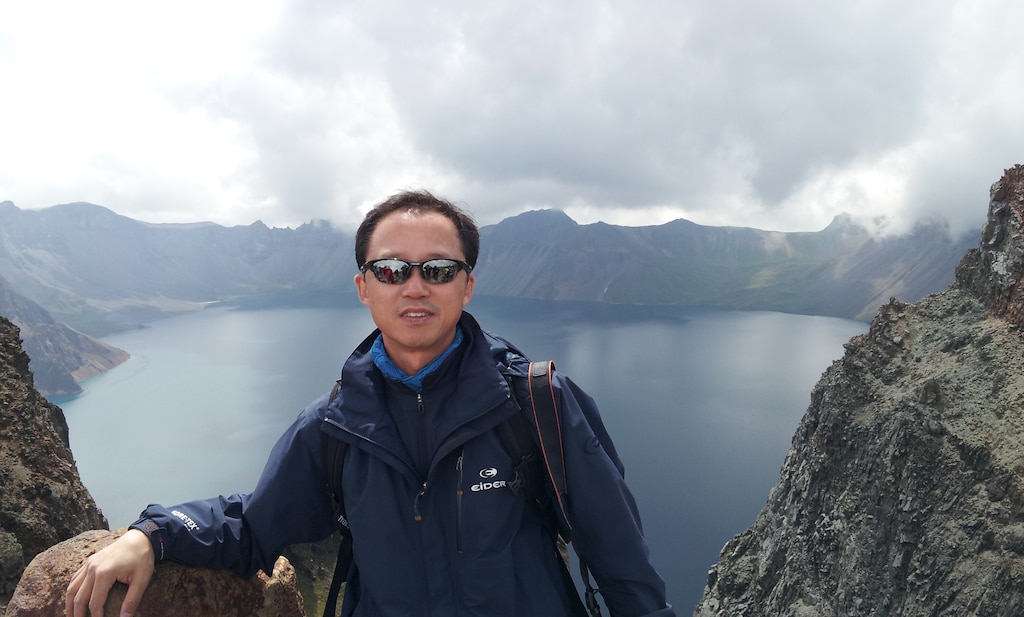 Dr. Pak Chun-pom, chief of the district’s data management section, poses for a picture in front of Heaven Lake, in the caldera atop Mount Baekdu. Mount Baekdu is an active volcano on the border of North Korea and China.