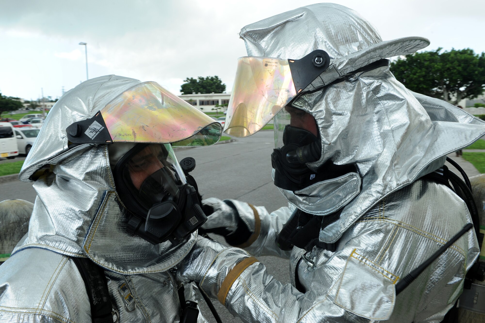 Two 18th Civil Engineer Squadron firefighters preform a buddy check before entering a smoke filled building during an exercise on Kadena Air Base, Japan Aug. 22, 2014. Firefighters perform buddy checks to ensure that all of their gear is functioning properly before putting their own lives at risk to save others. (U.S. Air Force photo by Airmen 1st Class Stephen G. Eigel/Released)