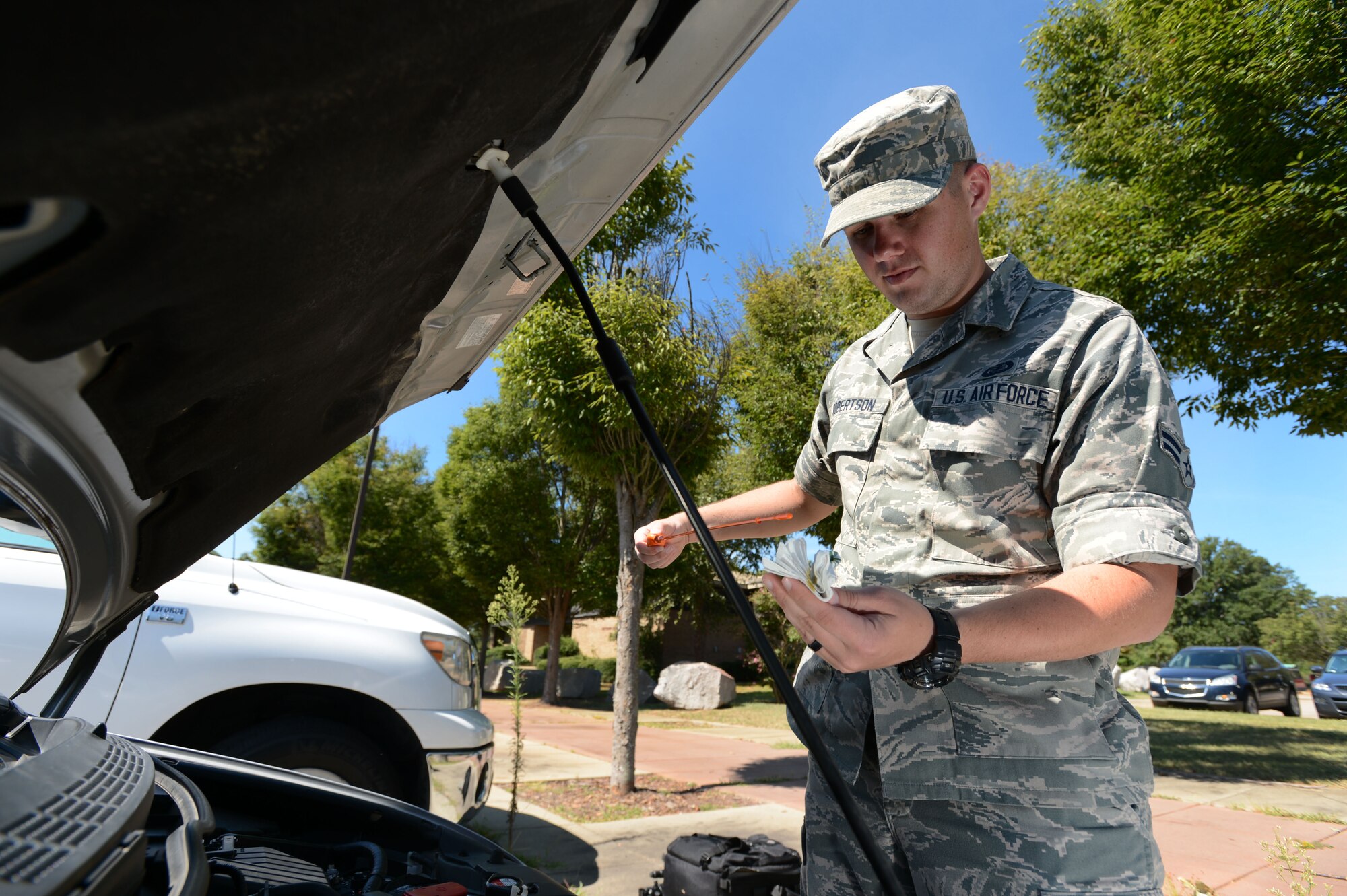 U.S. Air Force Airman 1st Class Chad Robertson, 20th Comptroller Squadron finance customer service technician, checks the oil in his vehicle at Shaw Air Force Base, S.C., Aug. 26, 2014. Though the Critical Days of Summer campaign is ending, Airmen should always remember to be safe in all they do. (U.S. Air Force photo by Airman 1st Class Jensen Stidham/Released)