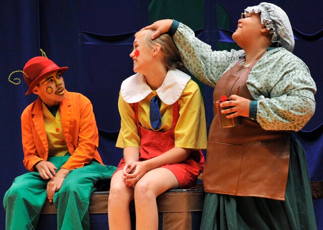 Jiminy Cricket (Alex Miranda, left) examines Pinocchio (Faith Quinslisk, center) after toymaker Mrs. Geppetto puts the final touches on her masterpiece wooden boy. The play “PINOCCHIO” ran Aug. 22 at the Malmstrom Air Force Base auditorium, and was presented by the 341st Force Support Squadron’s Youth Programs and the Missoula Children’s Theatre. (U.S. Air Force photo/John Turner)