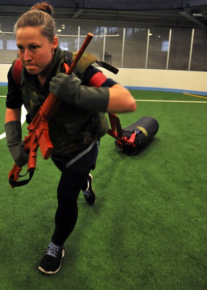Tech. Sgt. Mindy Tyson, 319th Force Support Squadron NCO in charge of career development, drags a weighted bag while carrying a simulated M16 rifle through a combat obstacle course during Summer Bash, Aug. 21, 2014, on Grand Forks, N.D. Summer Bash is an opportunity for Airmen to take a break from day-to-day tasks in order to boost morale, unit cohesion and espirt de corps. (U.S. Air Force photo/Senior Airman Xavier Navarro)
