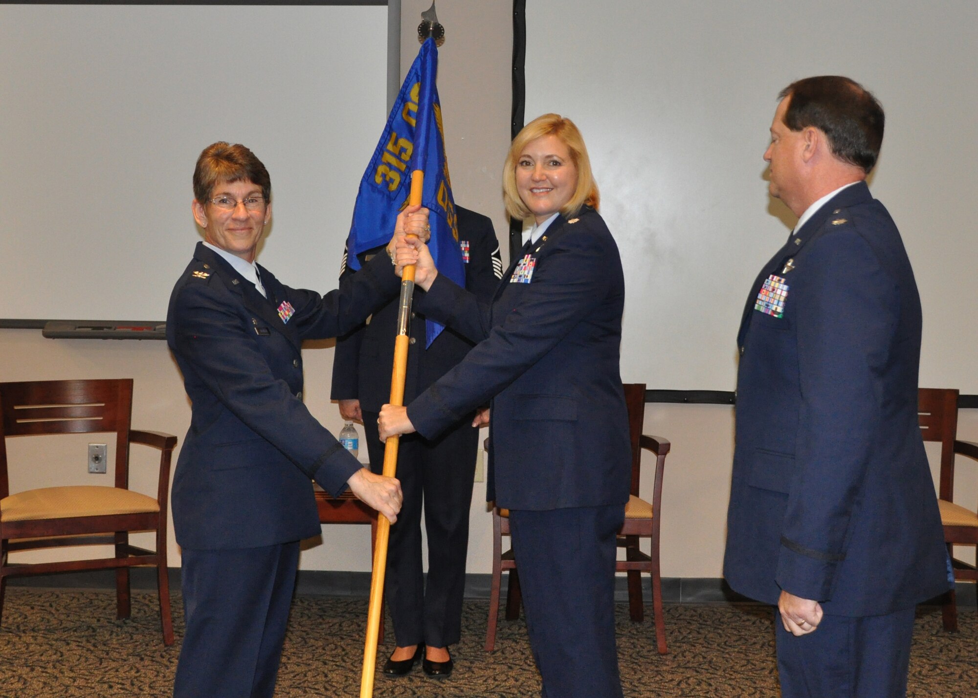 Col. Caroline Evernham, 315th Operations Group commander, passes the guidon to Lt. Col. Lara B. Morrison as she takes command of the 315th Operations Support Squadron during a ceremony Aug. 24, 2014 in the Yonkie Auditorium here at Joint Base Charleston, S.C. Lt. Col. Thomas McNamara relinquished command of the squadron to Morrison, whose previous assignment was with the18th Air Force at Scott Air Force Base, Ill. (U.S. Air Force photo / Capt. Michaela Judge)