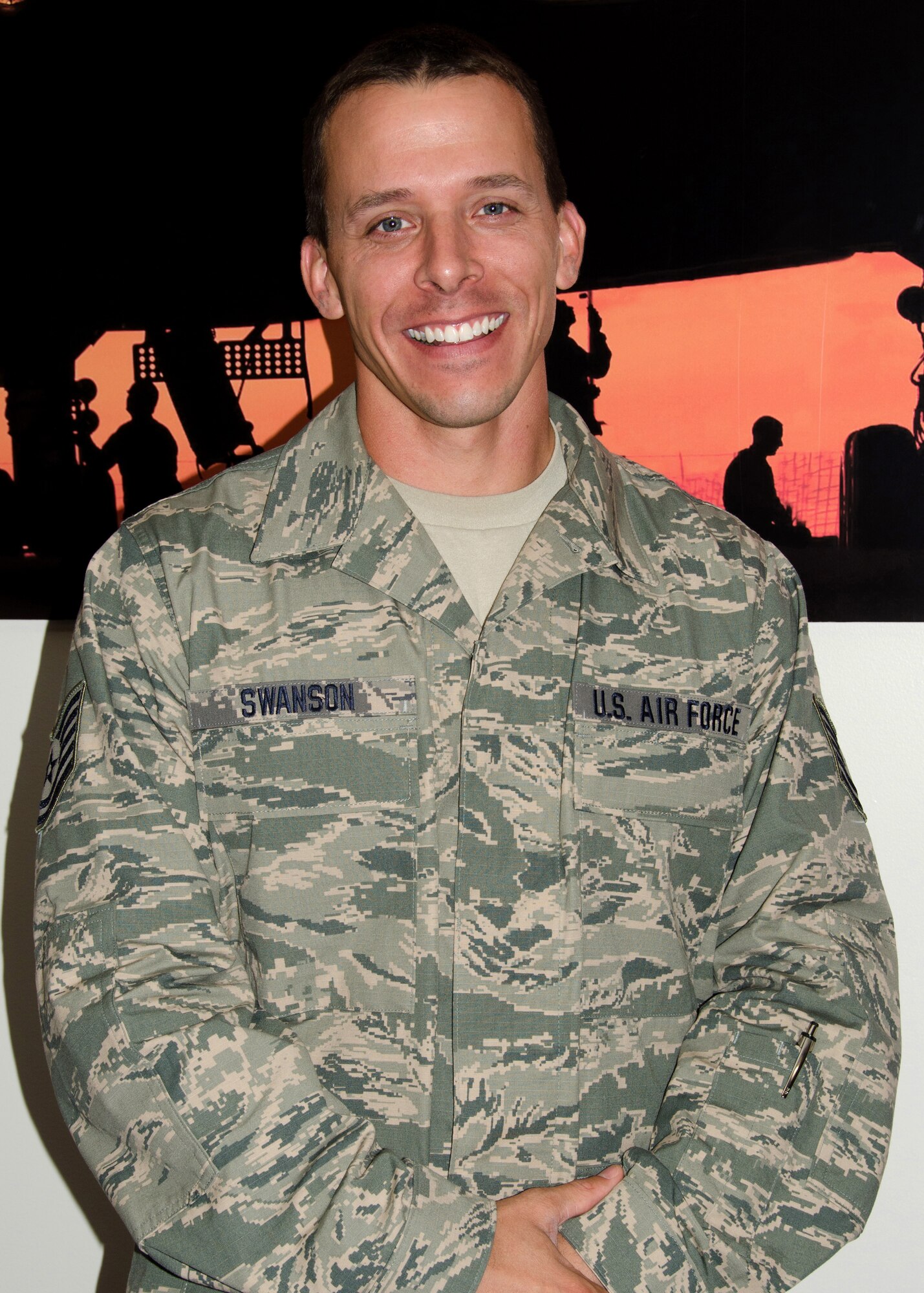 131st Bomb Wing, Missouri Air National Guard production recruiter Tech. Sgt. Joseph Swanson stands proudly before an image of the B-2 Spirit stealth bomber. “My goal is to try to spread the word because it’s not like we’re really selling anything. We’re just educating, because it really does sell itself,” said Swanson. (U.S. Air National Guard photo by Airman Halley Burgess/Released)