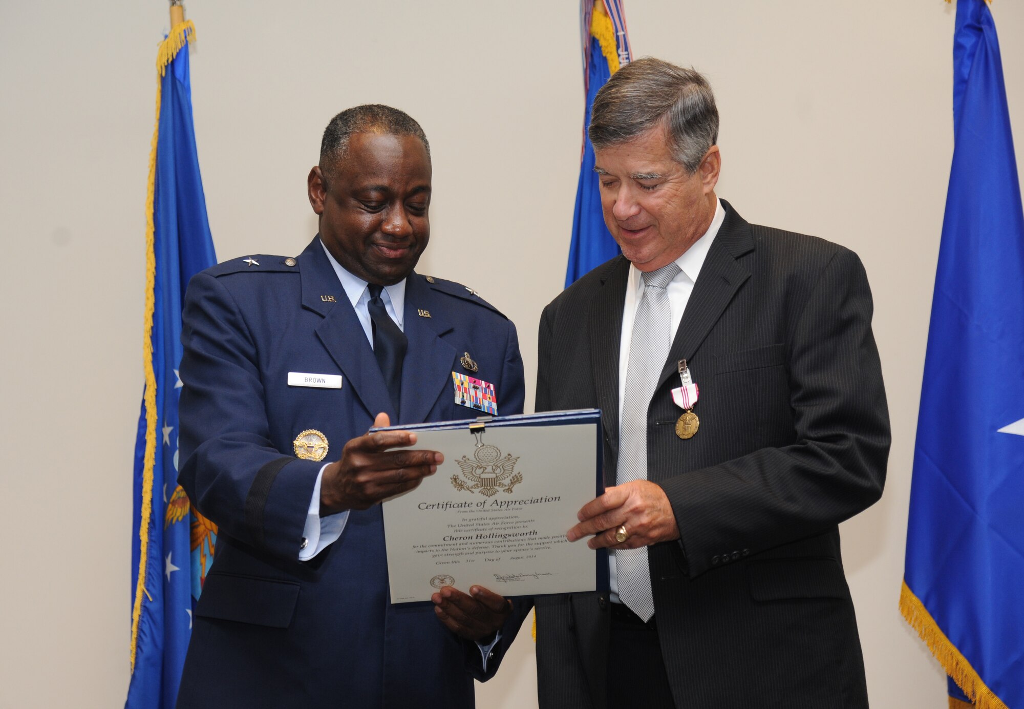 Brig. Gen. Mark Brown, 2nd Air Force commander, and James Hollingsworth, 2nd Air Force, review a certificate during Hollingsworth’s retirement ceremony Aug. 25, 2014, at the Roberts Maintenance Facility, Keesler Air Force Base, Miss.  He retired with more than 45 years of combined military and civilian service.  Brown was the officiating officer for the event. (U.S. Air Force photo by Kemberly Groue) 