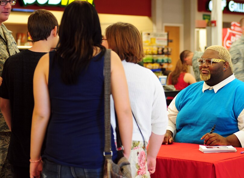 Willie Mike, MasterChef competitor, interacts with a family during an autograph signing in the Exchange Aug. 15, 2014, at Dyess Air Force Base, Texas. Many servicemembers and their families waited in line for a chance to meet and talk to the chef. (U.S. Air Force photo by Senior Airman Kia Atkins/Released)
