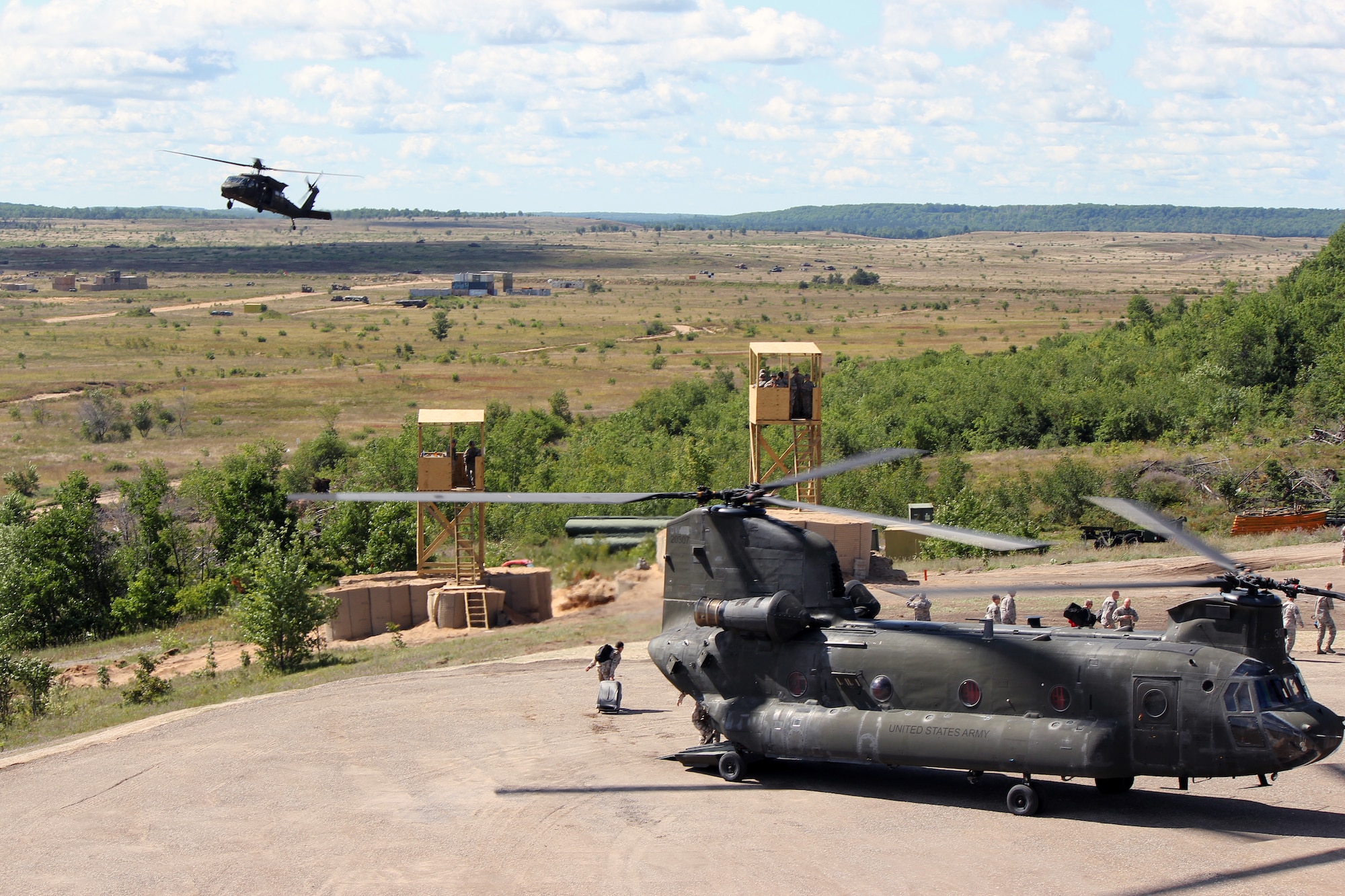 A UH-60 Black Hawk helicopter maneuvers into position after a CH-47 Chinook helicopter lands at the Grayling Air Gunnery Range during Operation Northern Strike, Aug. 13, 2014. Both aircraft are operated by the Michigan Army National Guard. Twenty-four units from 12 states and two coalition partners will participate in the three-week event. Operation Northern Strike will occur from Aug. 4 - 22, 2014, at the Alpena Combat Readiness Training Center and Camp Grayling Joint Maneuver Training Center. Over 300 Total Force fighter, bomber, mobility, and rotary sorties are planned in support of live fire exercises in order to meet stated objectives for participating units. (U.S. Air National Guard photo by Tech. Sgt. Dan Heaton)
