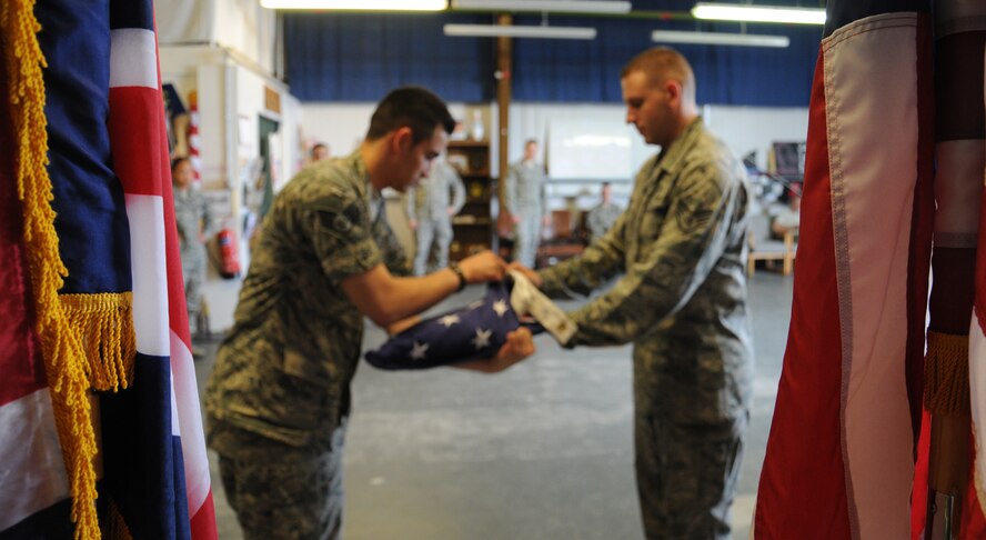 U.S. Air Force Staff Sgt. Aaron Klarenbach, left, 352nd Special Operations Maintenance Squadron aerospace propulsion journeyman from Vancouver, Wash., and U.S. Air Force Staff Sgt. James Stay, 100th Logistics Readiness Squadron flight service center supervisor from Chicago, Ill., practice flag folding during weekly honor guard training Aug. 5, 2014, on RAF Mildenhall, England. The honor guard is a huge part of events such as funerals, where a grieving family will look to the honor guard to represent the career, and life, their loved one was a part of. (U.S. Air Force photo/Gina Randall/Released)