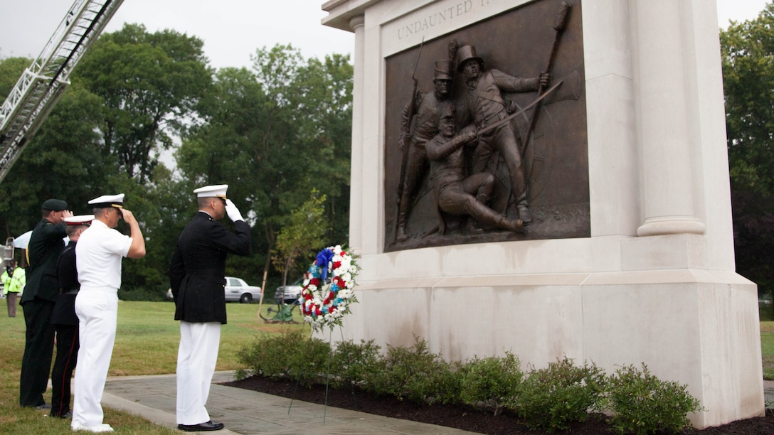 The “Undaunted in Battle” memorial to the Battle of Bladensburg, designed and sculpted by Joanna Blake, was dedicated at Bladensburg, Maryland, Aug. 23, 2014. The monument features a bronze sculpture of the end of the battle.  It depicts a wounded Commodore Joshua Barney, commander of the Chesapeake Flotilla, Charles Ball, a freed slave and flotilla man, and an unnamed Marine, in honor of the Marines who fought to the bitter end trying to repel British forces.