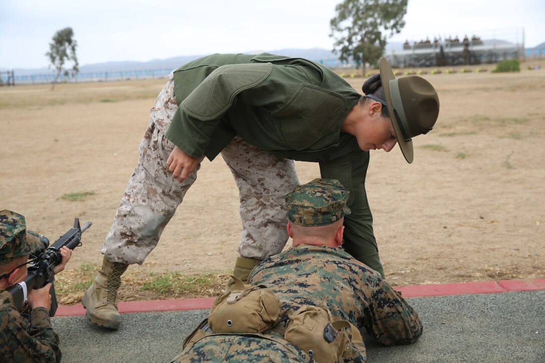 Sgt. Erin M. Fay, primary marksmanship instructor, Weapons and Field Training Battalion, Edson Range, Camp Pendleton, Calif., teaches a recruit the proper prone position during grass week, Aug. 13. Fay is only the second female to be in the PMI position at Edson Range. 