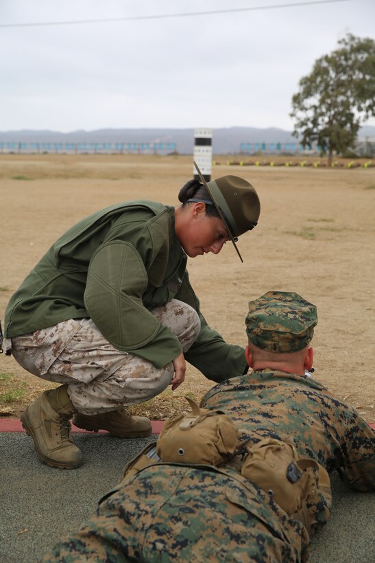 Sgt. Erin M. Fay, primary marksmanship instructor, Weapons and Field Training Battalion, Edson Range, Camp Pendleton, Calif., teaches a recruit the proper prone position during grass week, Aug. 13. Fay is only the second female to be in the PMI position at Edson Range. 