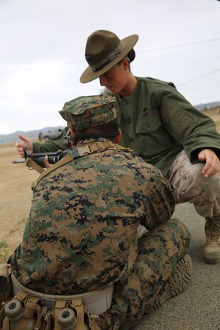 Sgt. Erin M. Fay, primary marksmanship instructor, Weapons and Field Training Battalion, Edson Range, Camp Pendleton, Calif., teaches a recruit the proper sitting position during grass week, Aug. 13. Fay is only the second female to be in the PMI position at Edson Range. 