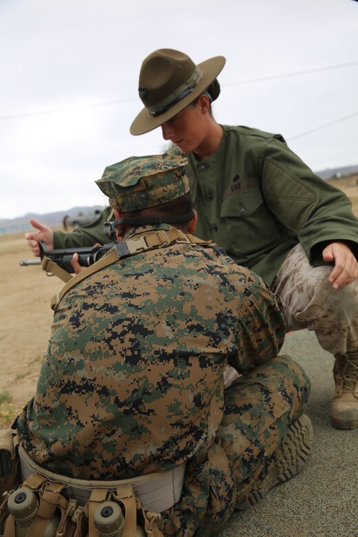 Sgt. Erin M. Fay, primary marksmanship instructor, Weapons and Field Training Battalion, Edson Range, Camp Pendleton, Calif., teaches a recruit the proper sitting position during grass week, Aug. 13. Fay is only the second female to be in the PMI position at Edson Range. 