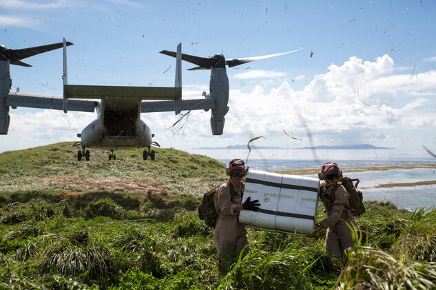 Lance Cpl. Zachary Swisher, left, and Lance Cpl. Cornelio Vasquez, ordnancemen with Marine Aerial Refueler Squadron 152, carry a container of GTR-18 missiles, better known as "Smokey SAMs," away from an MV-22B Osprey during a threat reaction evolution on an island outside of Okinawa, Japan, Aug. 26, 2014. The threat reaction evolution is a chance for pilots to stay up to date on their qualifications while keeping an alert and aware mindset for any arising combat scenario.