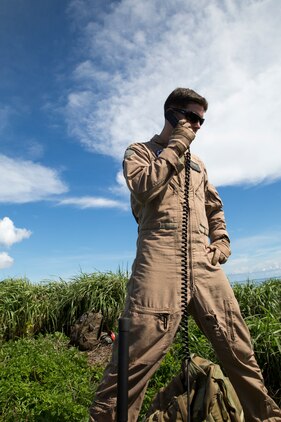 Sgt. Korey Norman, quality assurance safety observer with Marine Aerial Refueler Squadron 152, communicates with a pilot of a KC-130J Super Hercules during a threat reaction evolution on an island outside of Okinawa, Japan, Aug. 26, 2014. The threat reaction evolution is a chance for pilots to stay up to date on their qualifications while keeping an alert and aware mindset for any arising combat scenario.