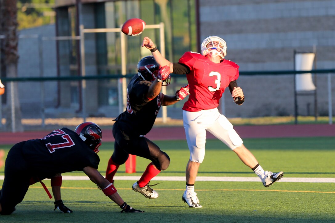 Helsup Locklear, Marine Corps Air Station Miramar Falcons’ defensive tackle, rushes the Headquarters Battalion, 1st Marine Division quarterback, forcing an interception during the Falcons’ season opener at Paige Field House aboard Marine Corps Base Camp Pendleton, Calif., Aug. 26. The Falcons defeated the Standard Bearers 19-8 for the first game of the season.