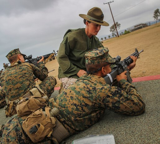 Sgt. Erin M. Fay, primary marksmanship instructor, Weapons and Field Training Battalion, Edson Range, Camp Pendleton, Calif., teaches a recruit the proper prone position during grass week, Aug. 13. Fay is only the second female to be in the PMI position at Edson Range.