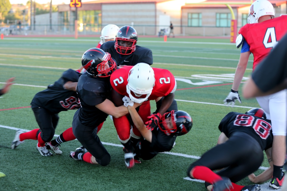 A cast of Marine Corps Air Station Miramar Falcons drag down a Headquarters Battalion, 1st Marine Division running back during a game at Paige Field House aboard Marine Corps Base Camp Pendleton, Calif., Aug. 26. The Falcons defeated the Standard Bearers 19-8.