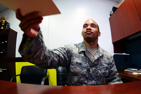 Staff Sgt. Terrance Dixon, 14th Fighter Squadron, hands a folder to a customer at the 14 FS Aircraft Maintenance Unit at Misawa Air Base, Japan, Aug. 25, 2014. Dixon's job as a knowledge operations specialist postures him to be able to work with all DoD departments seamlessly. (U.S. Air Force photo/Staff Sgt. Derek VanHorn)