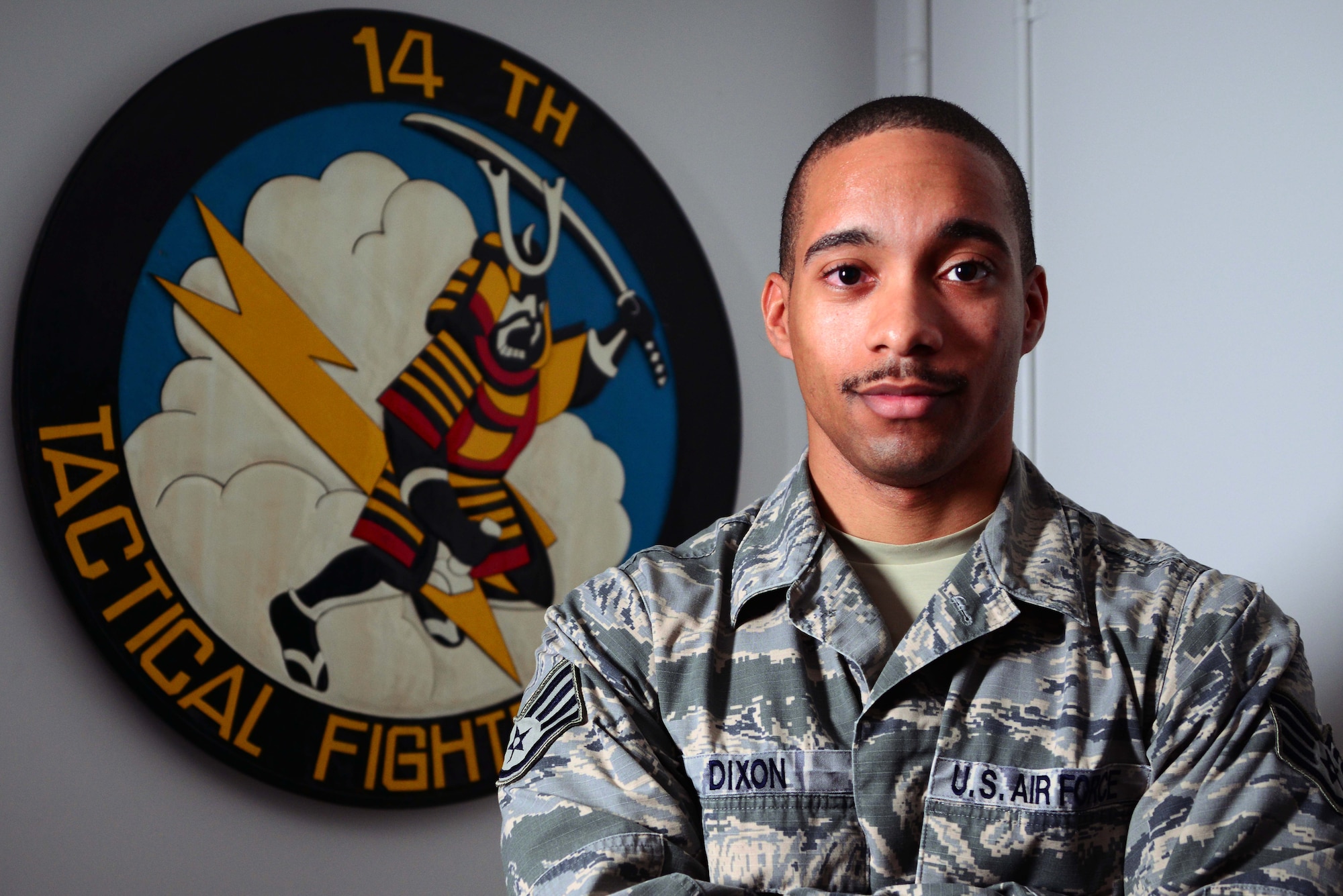 Staff Sgt. Terrance Dixon, 14th Fighter Squadron, stands next to his squadron's seal at the 14 FS Aircraft Maintenance Unit at Misawa Air Base, Japan, Aug. 25, 2014. Dixon works as a knowledge operations specialist and assists 14 FS personnel with various additional duties. (U.S. Air Force photo/Staff Sgt. Derek VanHorn) 