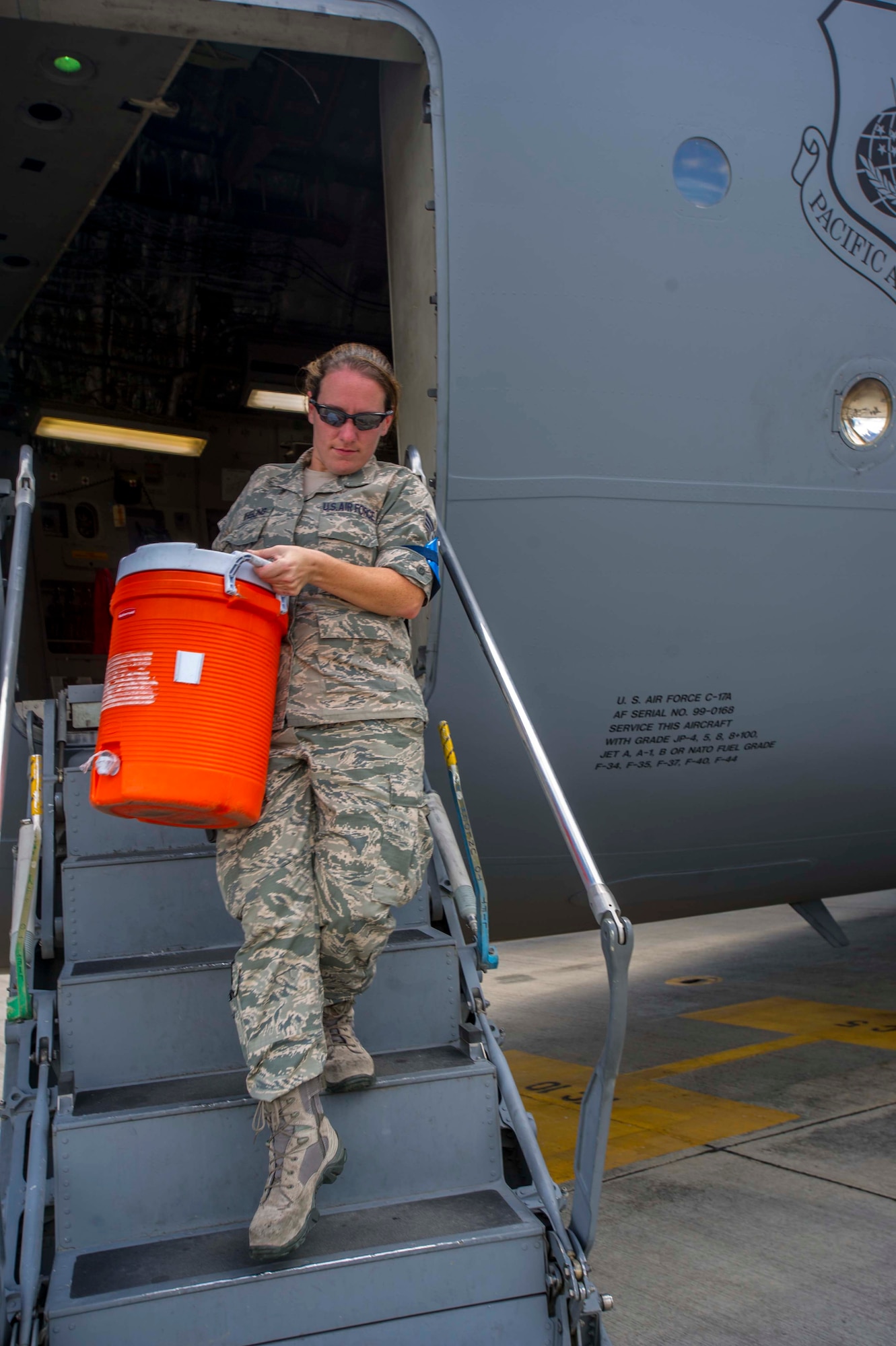 Senior Airman Amanda Wheeling, 735th Air Mobility Squadron air transportation journeyman, removes a cooler of ice water from a C-17 Globemaster III during the de-fleeting process on the Joint Base Pearl Harbor-Hickam, Hawaii, flightline Aug. 26, 2014. During de-fleeting, fleet services Airmen clean and remove the trash and waste water from aircraft. (U.S. Air Force photo by Tech. Sgt. Terri Paden)