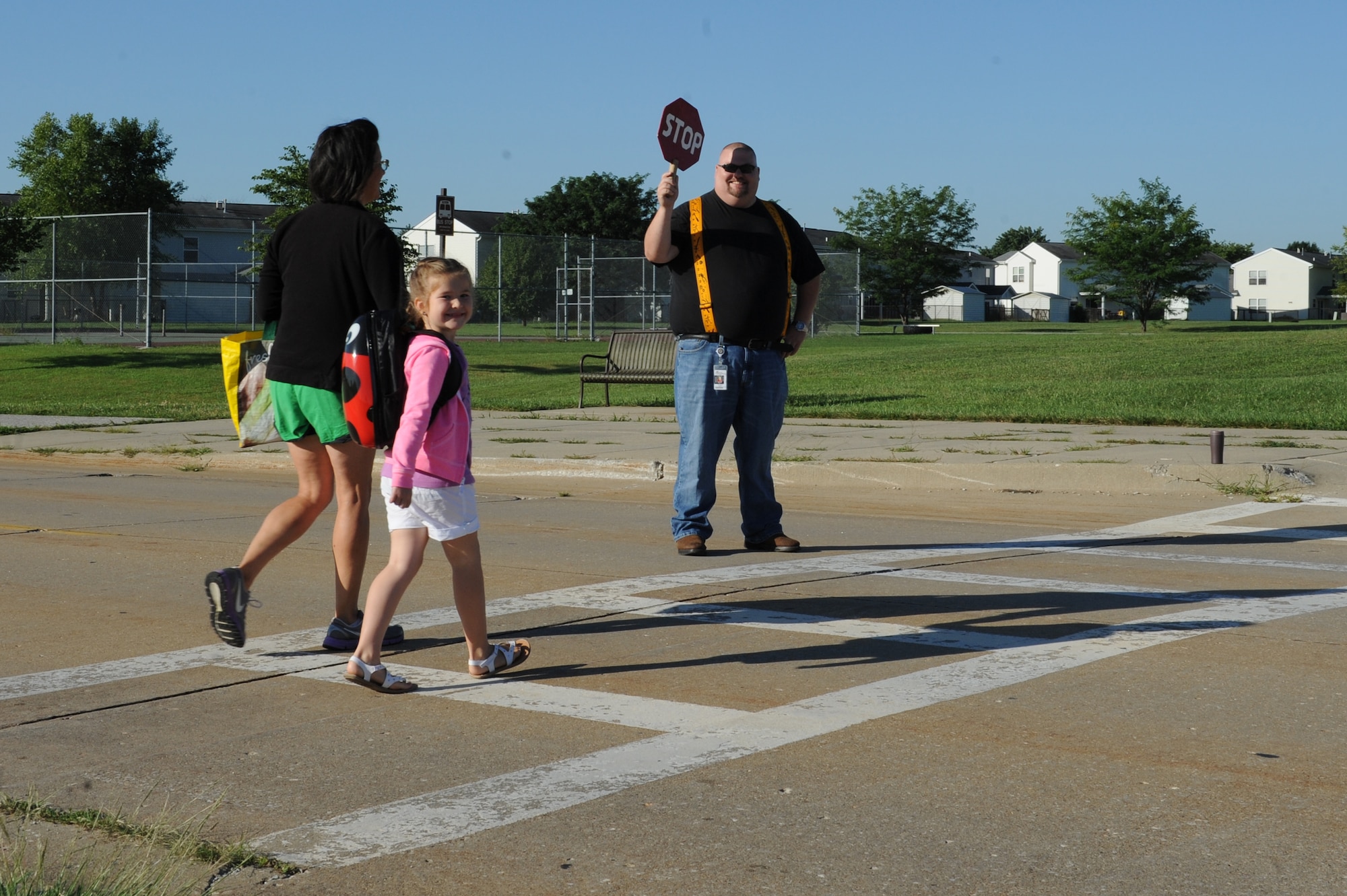 A student and her mother are greeted by a crossing guard at Scott Elementary School on the first day of school, August 13, 2014, at Scott Air Force Base, Ill. Crossing guards ensure students who cross from base housing or the youth center to Scott Elementary School are safe in the crosswalk, where the speed limit is 15 miles per hour. (U.S. Air Force photo by Senior Airman Sarah Hall-Kirchner/Released)